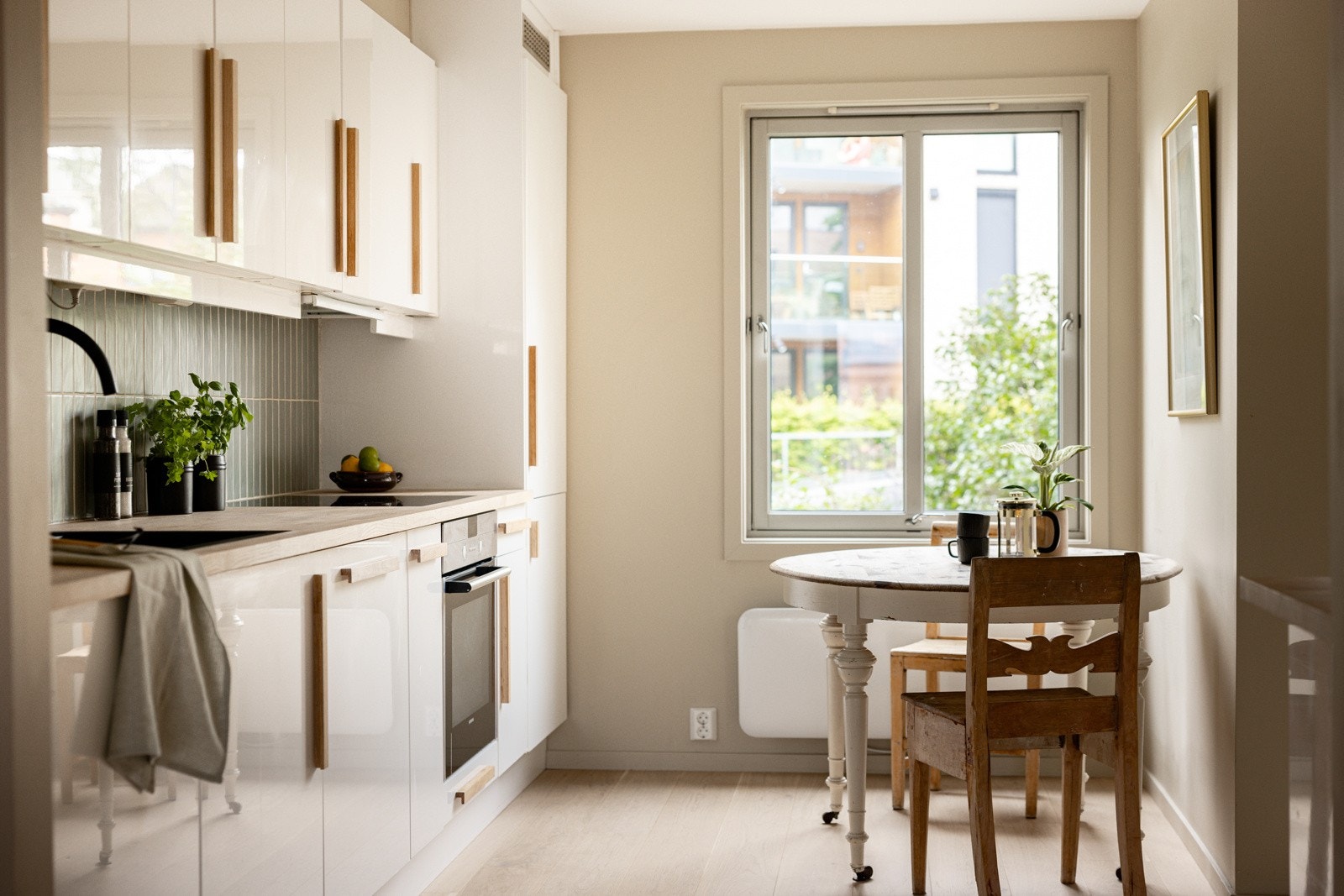 Moderne kjøkkeninnrending med hvite glatte fronter og håndtak og benkeplate i hvitoljet eik. Galleribilde