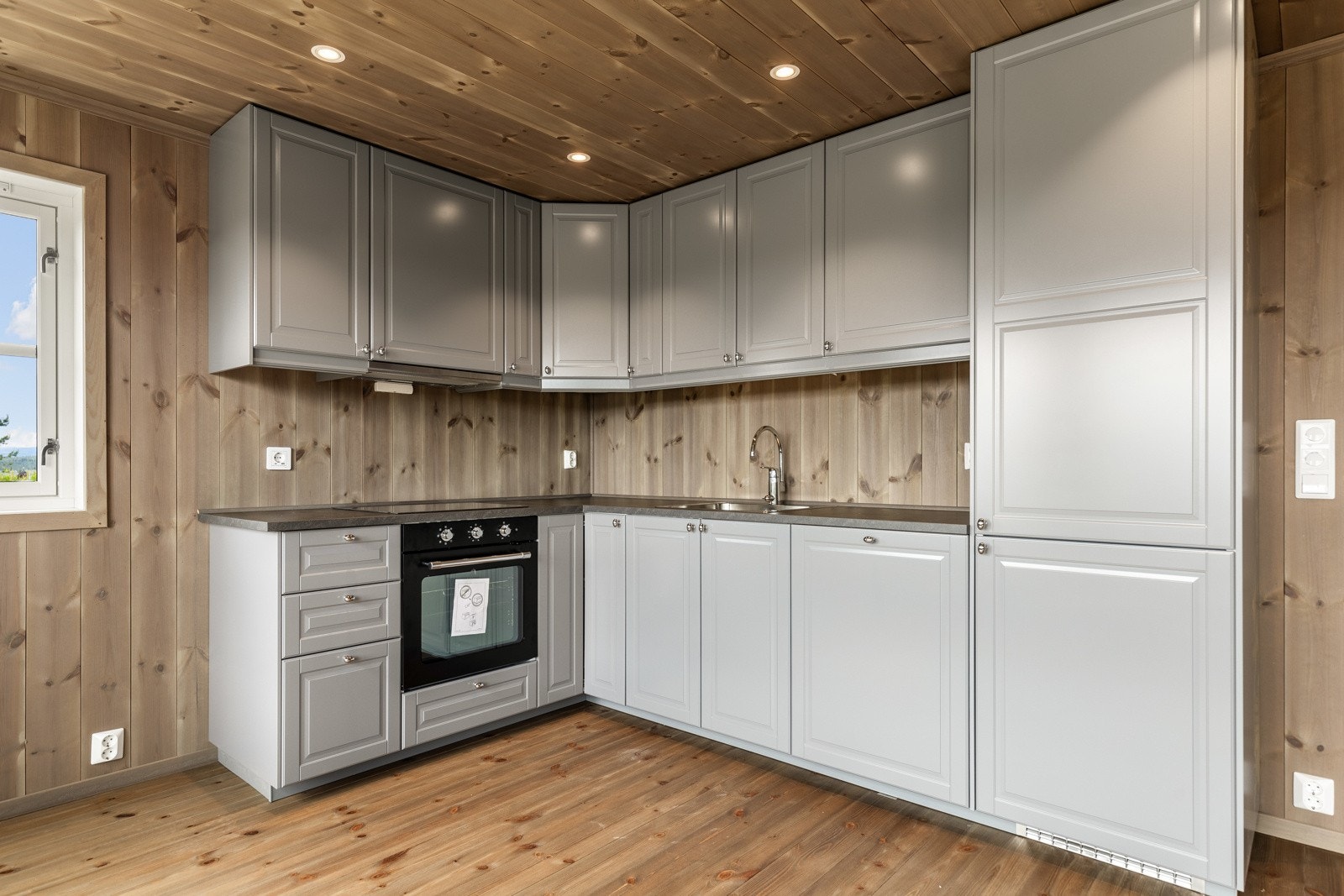 Kjøkkenet er utstyrt med moderne hvitevarer, inkludert en stilren komfyr, oppvaskmaskin, kjøleskap med fryser og mikrobølgeovn, samt rikelig med skapplass. Galleribilde