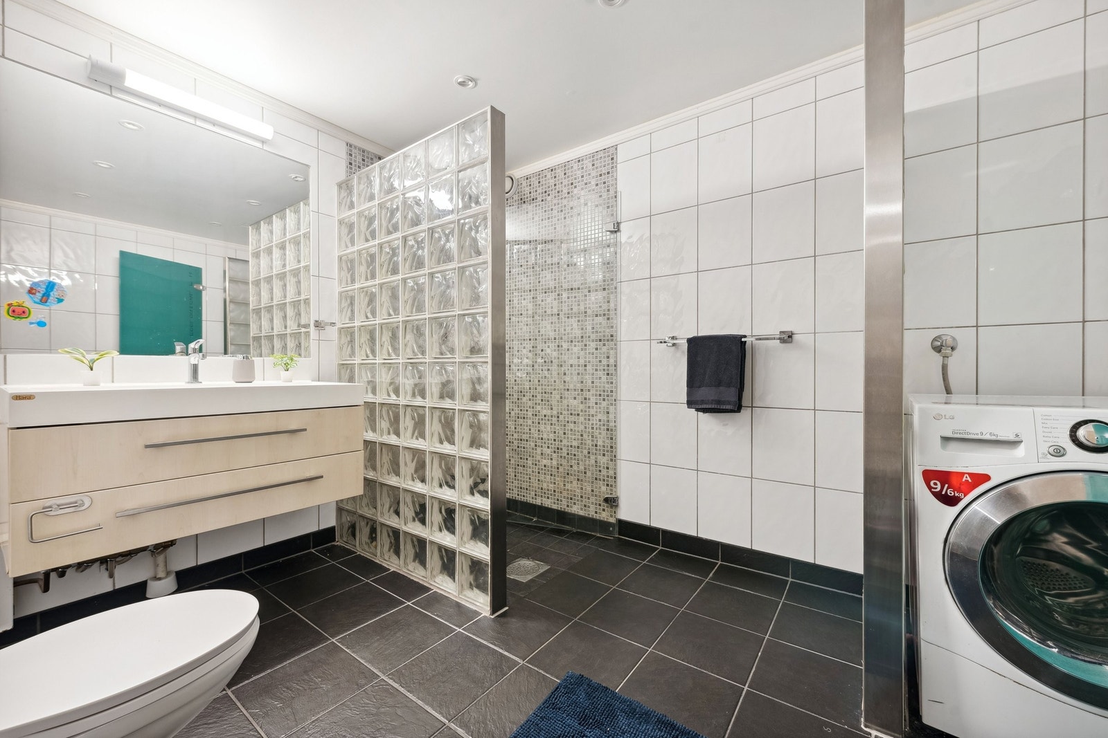 Fra gangen ligger badet, med vegghengt toalett, stor dusj og vaskenisje. Galleribilde