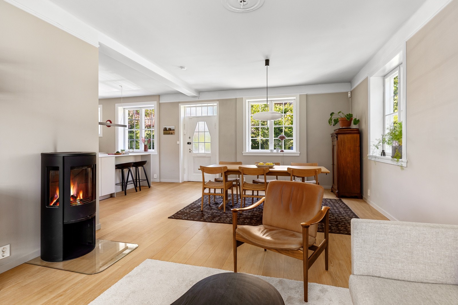 Gjennomgående planløsning og vinduer på tre av fire vegger gir mye naturlig lys, med stuen åpen mot spisestuen. Peis fra Conutra Galleribilde