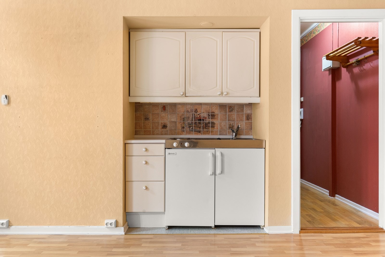 Enkel kjøkkeninnredning med integrert benkekjøleskap, oppvaskkum og platetopp. Galleribilde