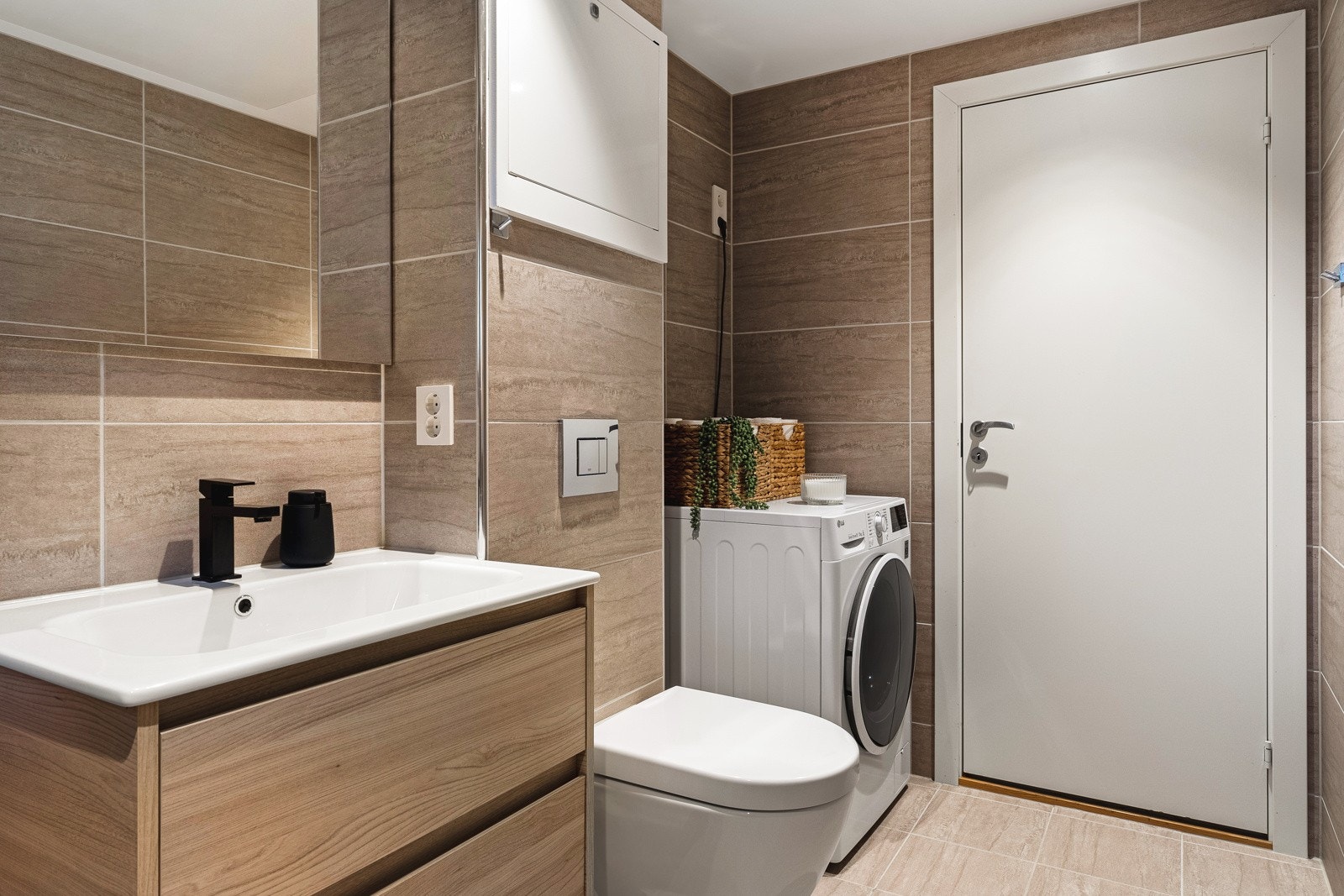 Badet er innredet med dusj m/glassvegg, vegghengt toalett, baderomsinnredning og opplegg for vaskemaskin. Galleribilde