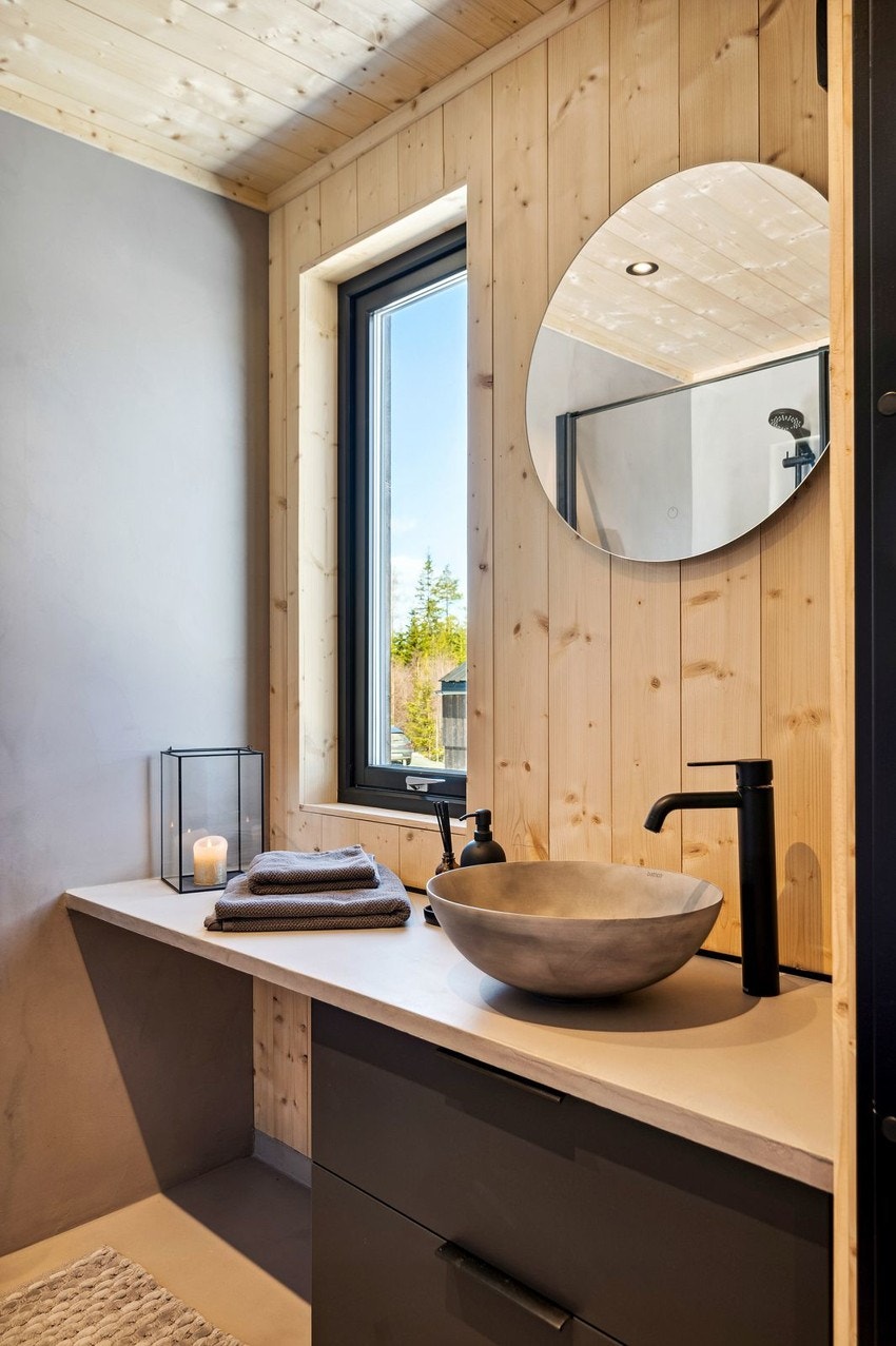 Badet har vegghengt toalett, servant og dusj med foldbare dører. Mikrosement på gulv, vegger og servant. Galleribilde