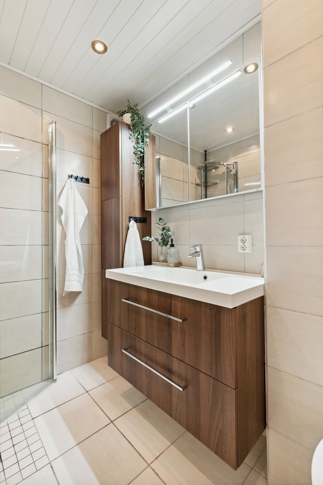 Innredningen har heldekkende servant med underskap, speilskap med lys, høyskap, vegghengt toalett og dusjhjørne med innfellbare glassdører for optimal romutnyttelse. Galleribilde