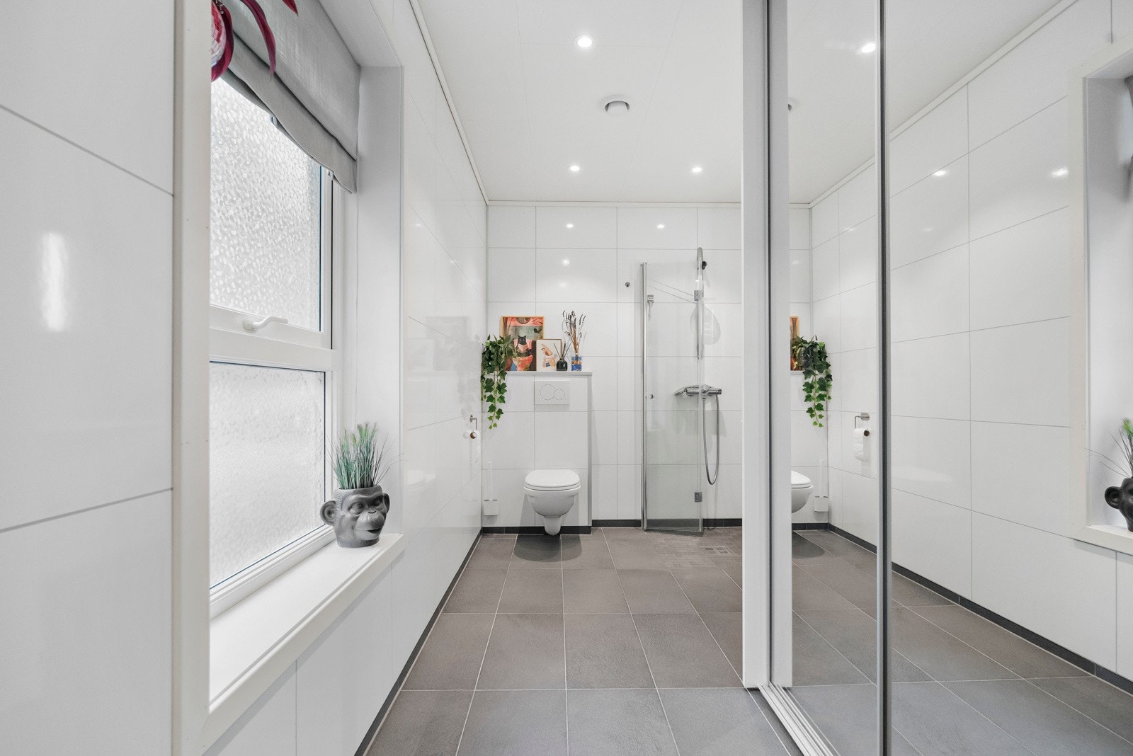 Kombinert bad/vaskerom med skyvedørsgarderobe framfor vaskemaskin Galleribilde