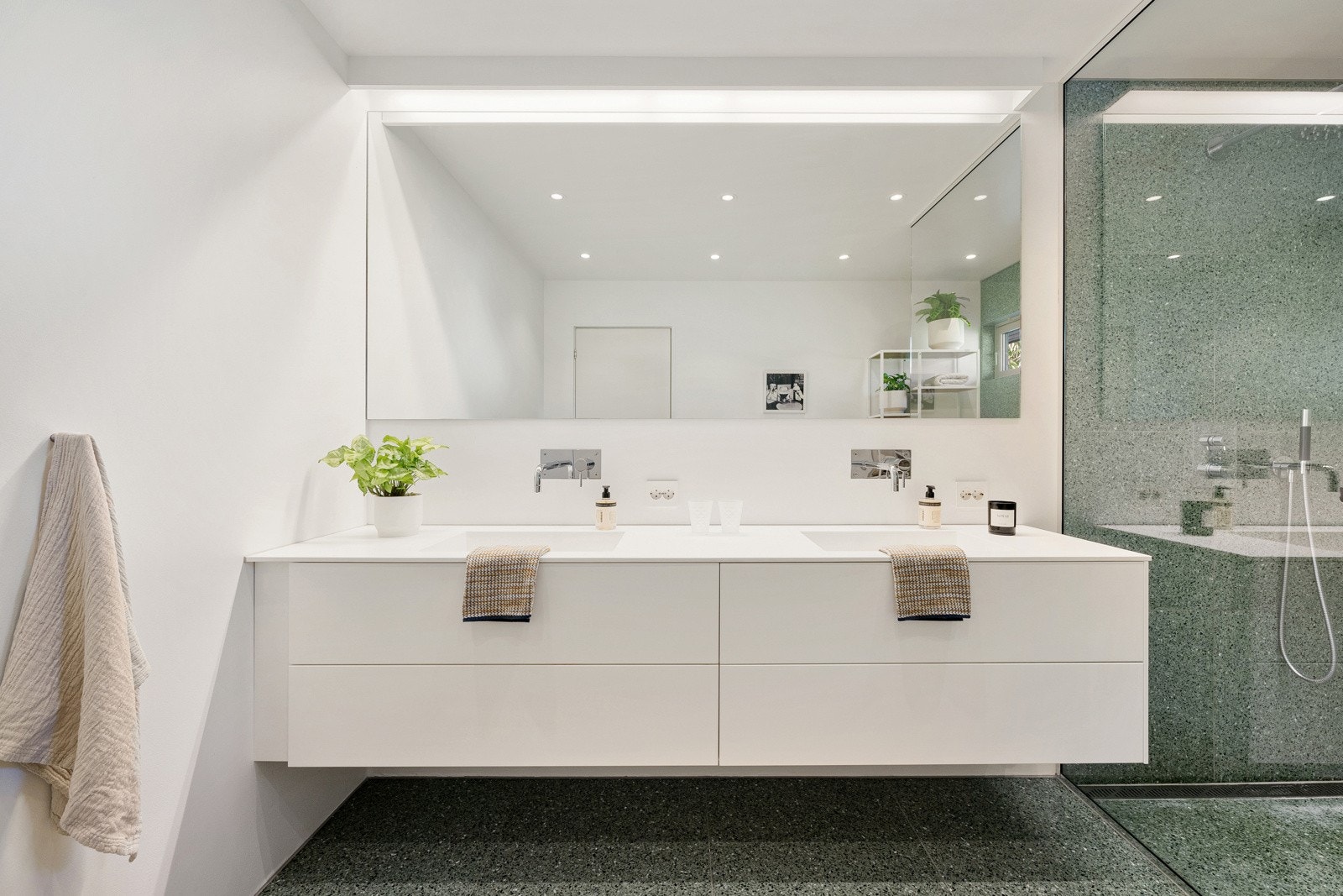 Det ene badet ligger i første etasje og her er det hvite, slette veggflater og store spesialimporterte terrazzofliser i grønt i romslig dusjsone. Galleribilde