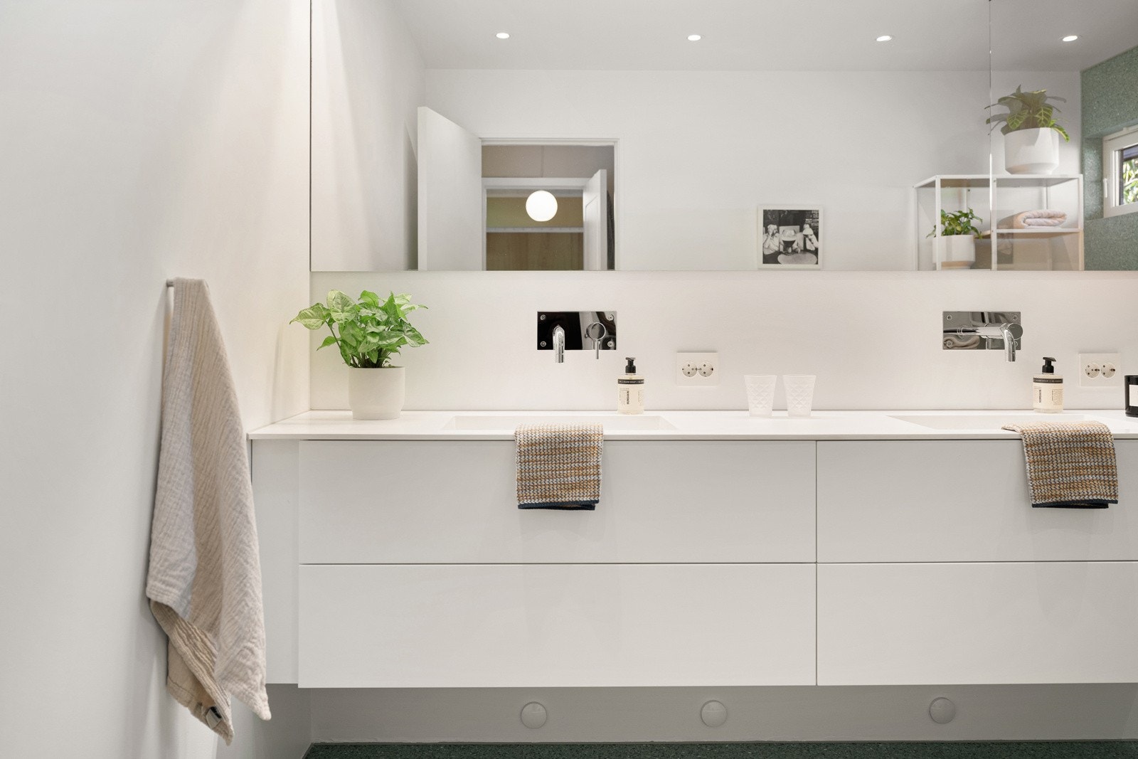 Baderomsinnredningen er i hvit, slett utførelse og består av vegghengt skuffeseksjon, spesialbygd servant i Corian og speil med belysning. Galleribilde