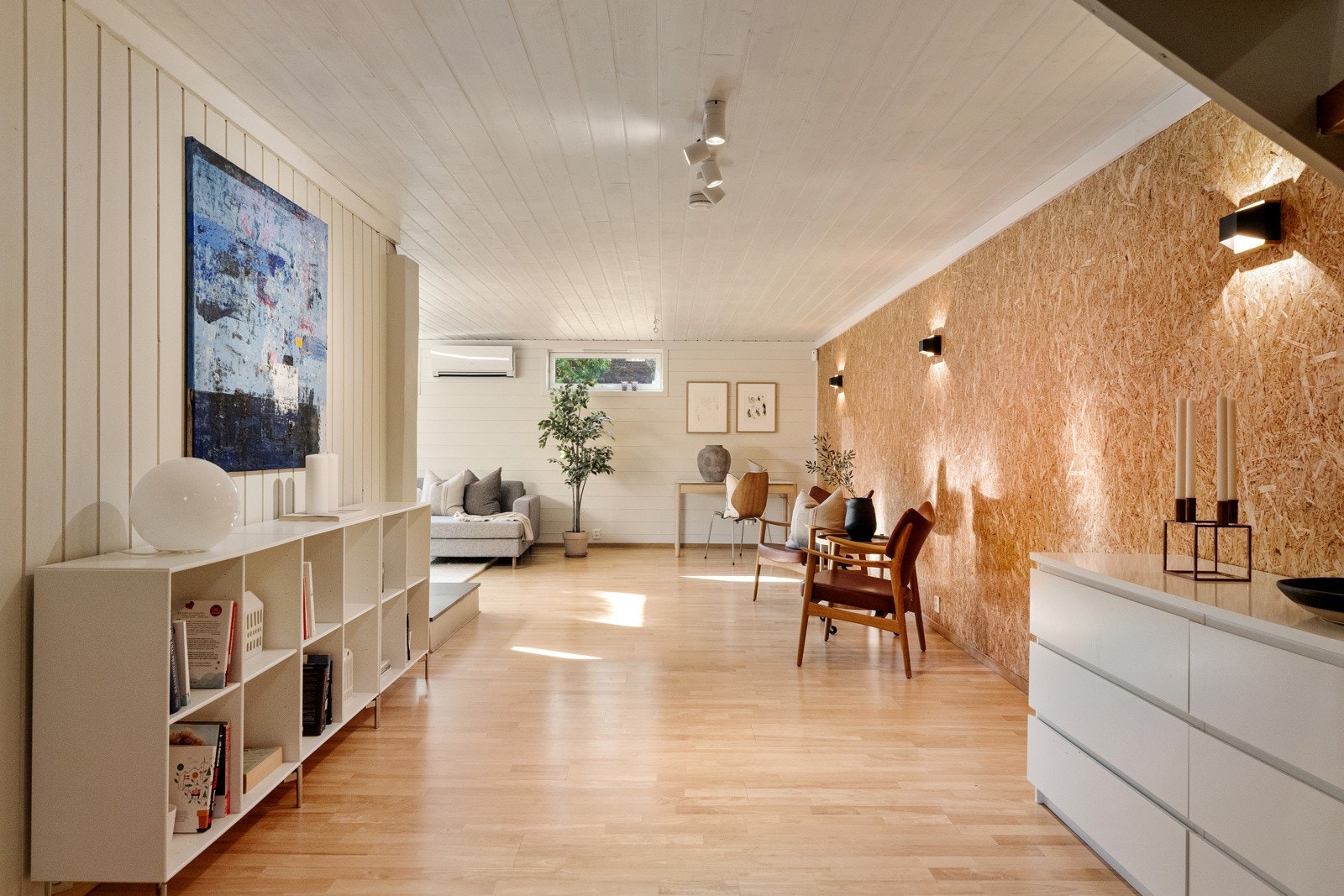 Rommet har parkett på gulvet, lysmalt panel på veggene og én vegg med sponplater. Galleribilde