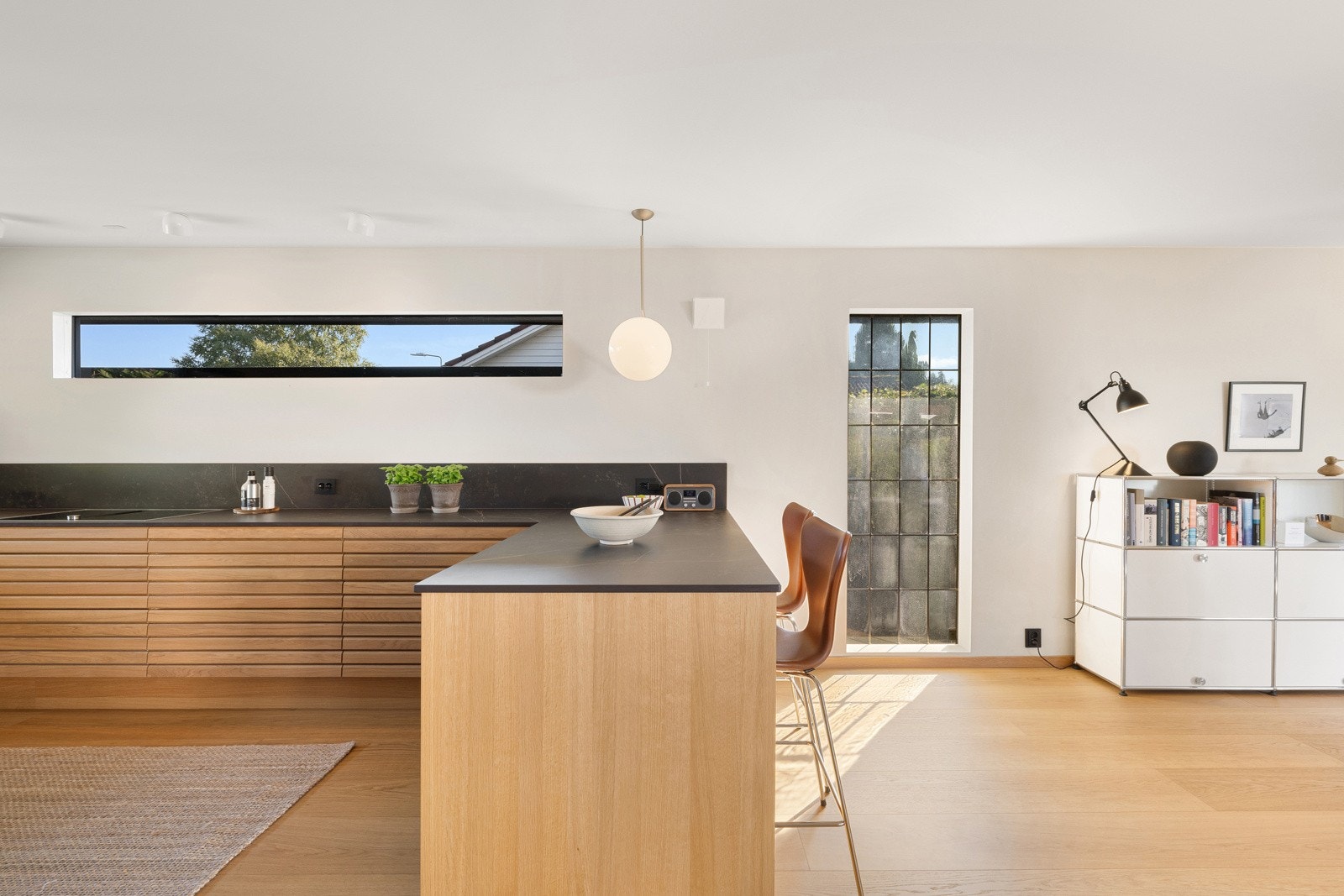 Innredningen er bygget i en hendig kvadrat, med høyskap på én side, gode arbeidsbenker og en halvøy med spiseplass ut mot stuen. Galleribilde