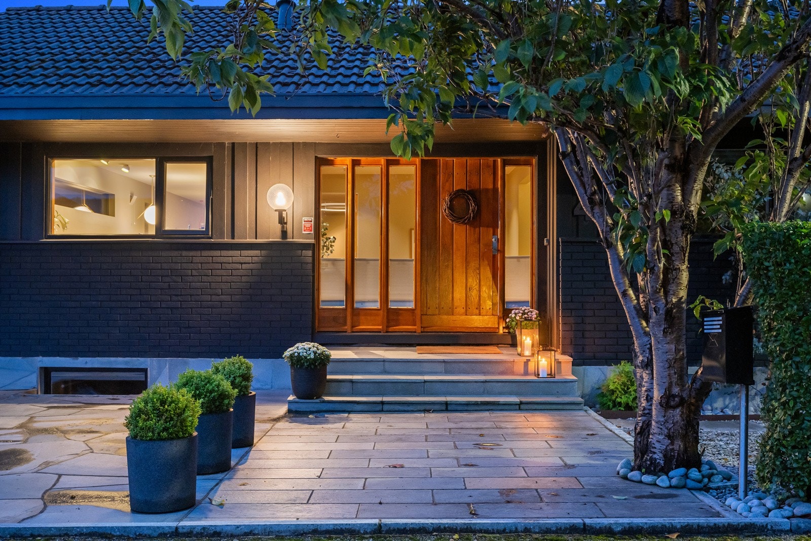 Inngangspartiet er dels overbygd og har teakdør med flere sideglass. Glassene bidrar til en herlig lyssetting av entreen innenfor. Galleribilde