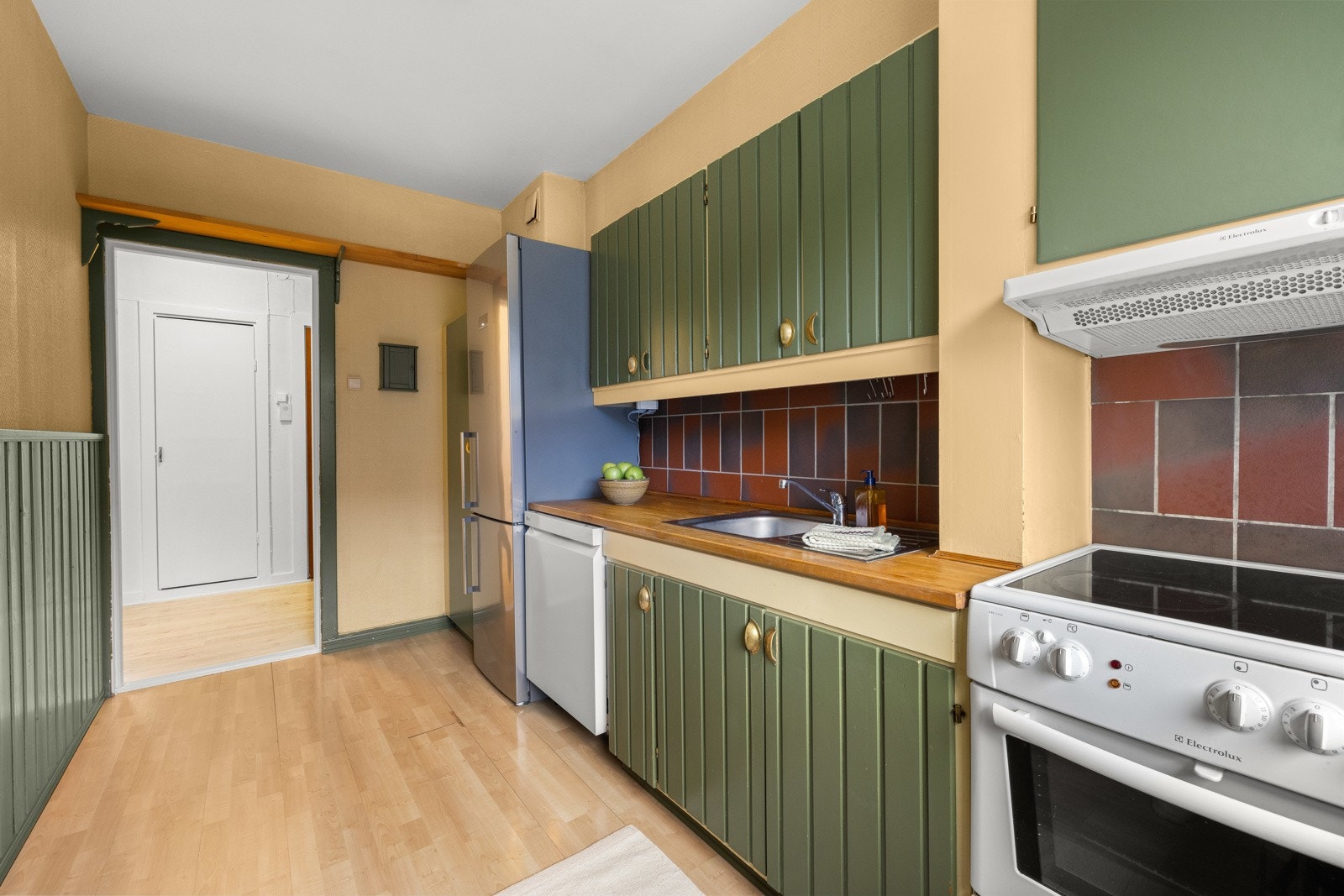 Fra entreén kommer du rett til kjøkkenet som har vegger med malt strietapet og grønnmalt brystningspanel, samt gulvflate belagt med parkett. Galleribilde