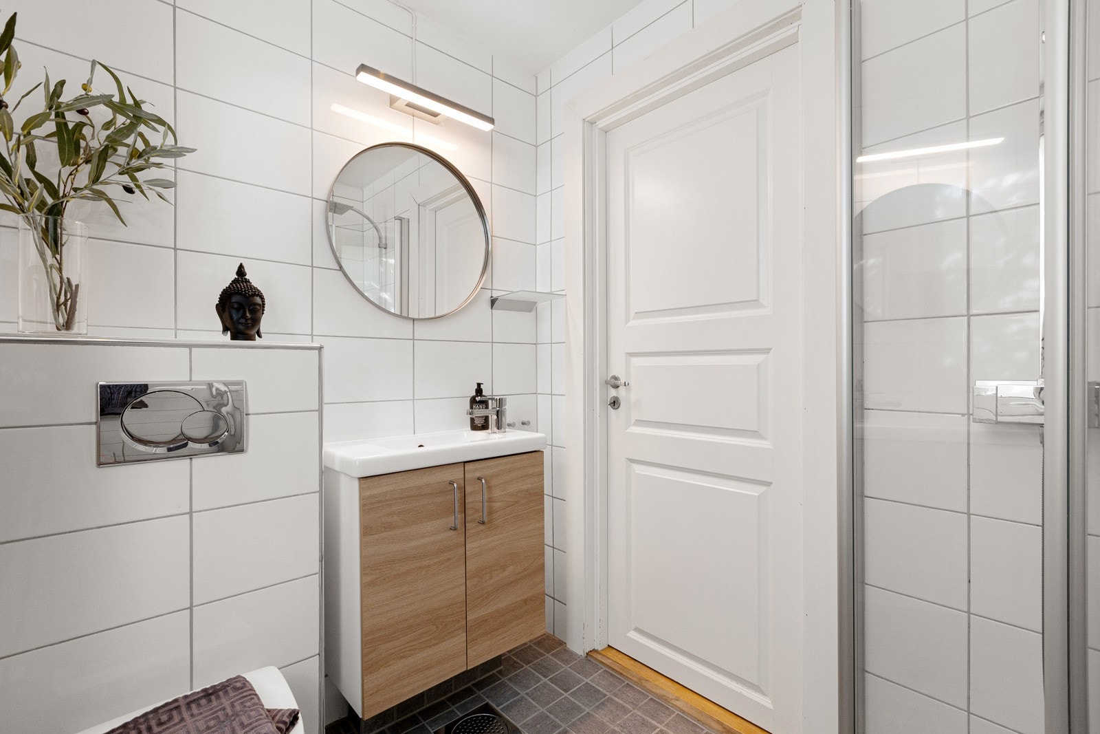 På badet er det vegghengt toalett, servant med underskap, høyskap og dusj med dører i herdet glass. Videre er det opplegg for vaskemaskin. Galleribilde