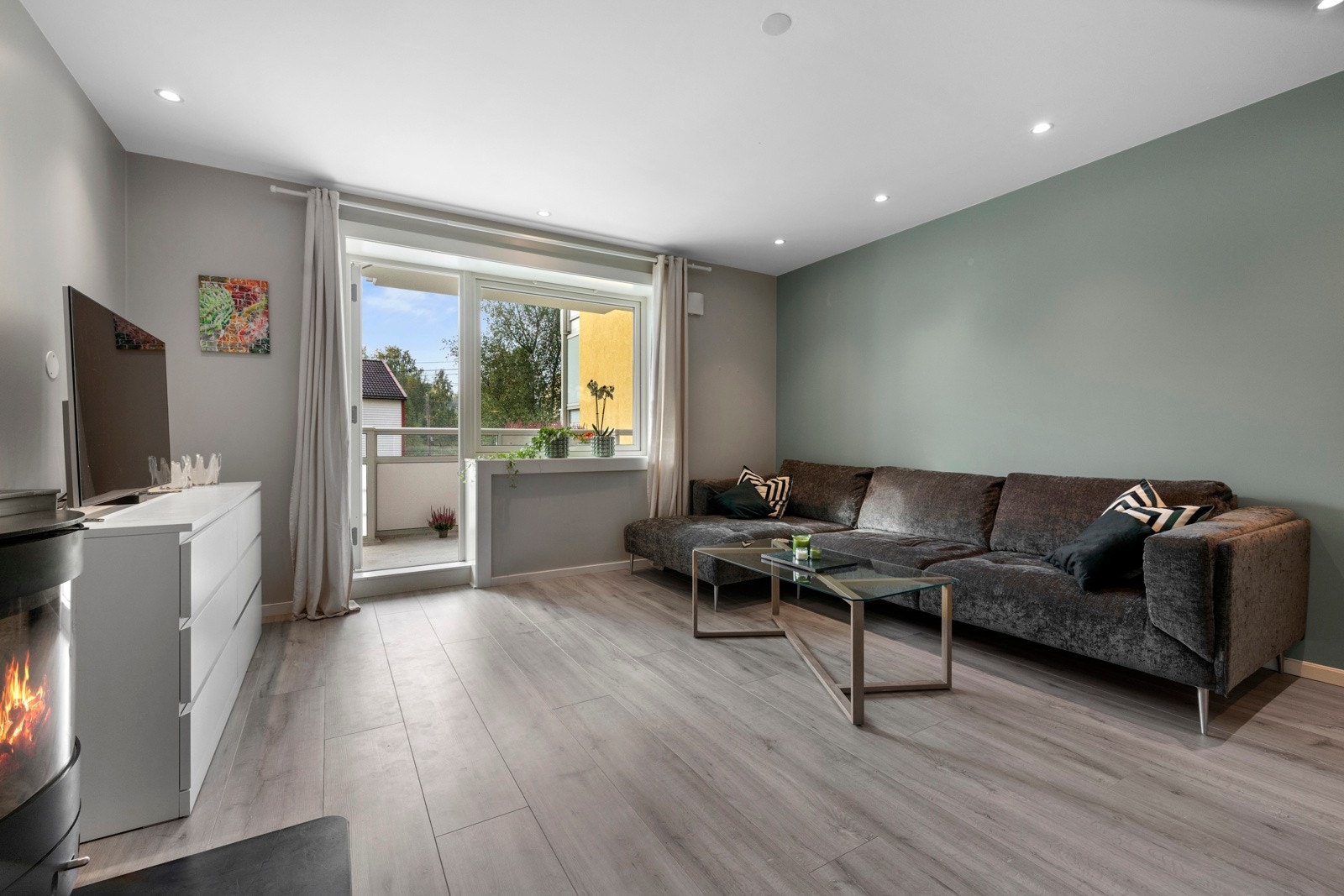 Den flotte stuen har laminatgulv, downlights, dus naturtone på vegger og kontrastvegg malt i en harmonisk fargetone Galleribilde
