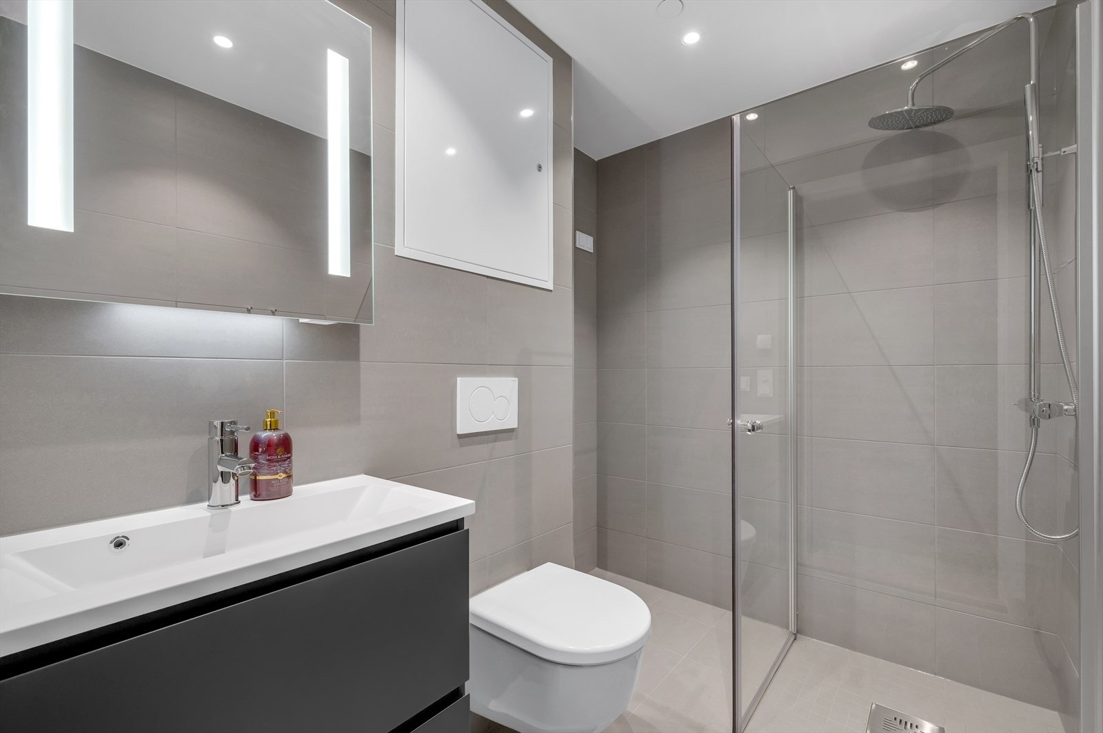 Delikat flislagt bad med vannbåren gulvvarme og downlights i himling. Badet inneholder servant med skuffer og speil med lys. Galleribilde