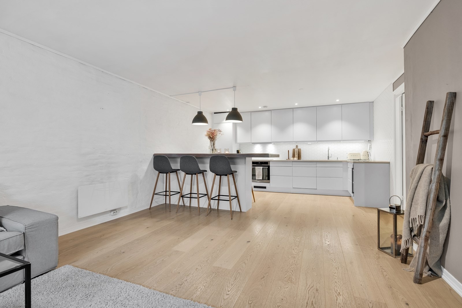Stor og sosial stue i åpen kjøkkenløsning med 1-stavs parkett på gulv. Galleribilde