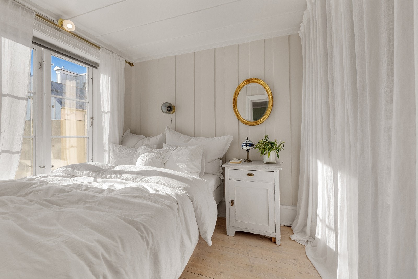 Veggene er malt i en lys, beige-tone, hvilket bidrar til et svalt men lunt soveværelse. Galleribilde