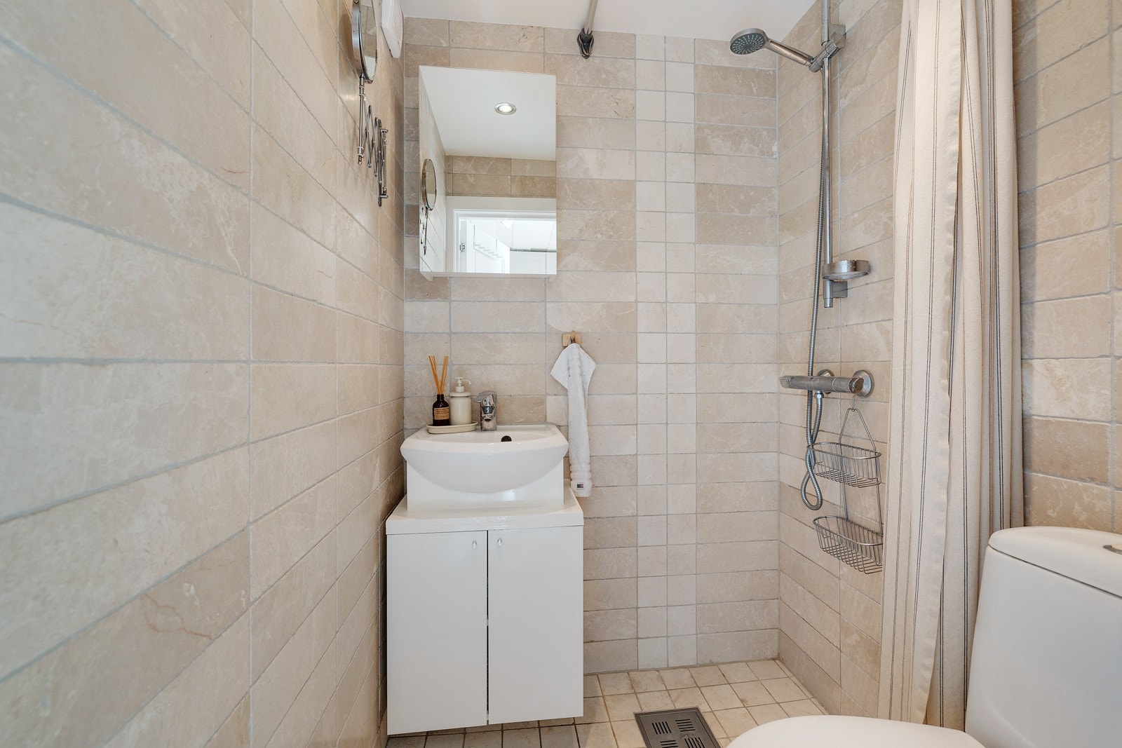 Badet inneholder servantinnredning med ovenpåliggende servant med ett-greps armatur, samt veggmontert speil. Galleribilde