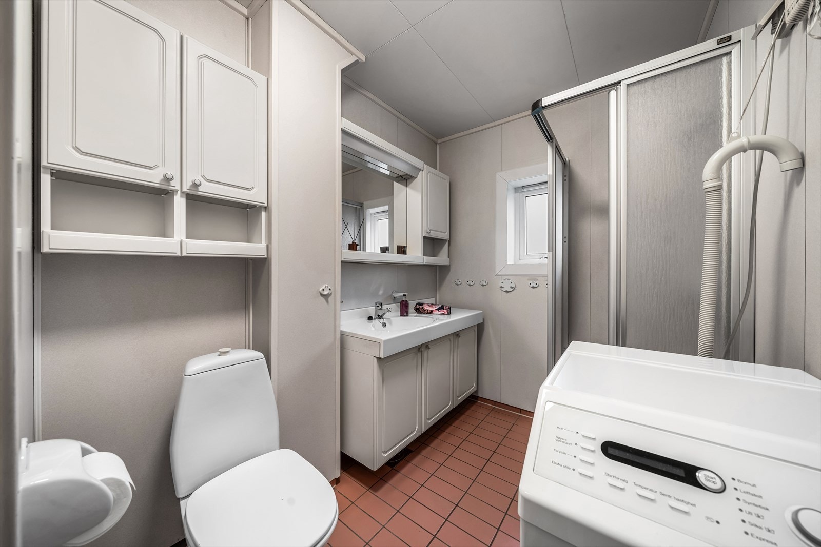 Bad med innredning med rikelig oppbevaringsplass og opplegg for vaskemaskin. Galleribilde