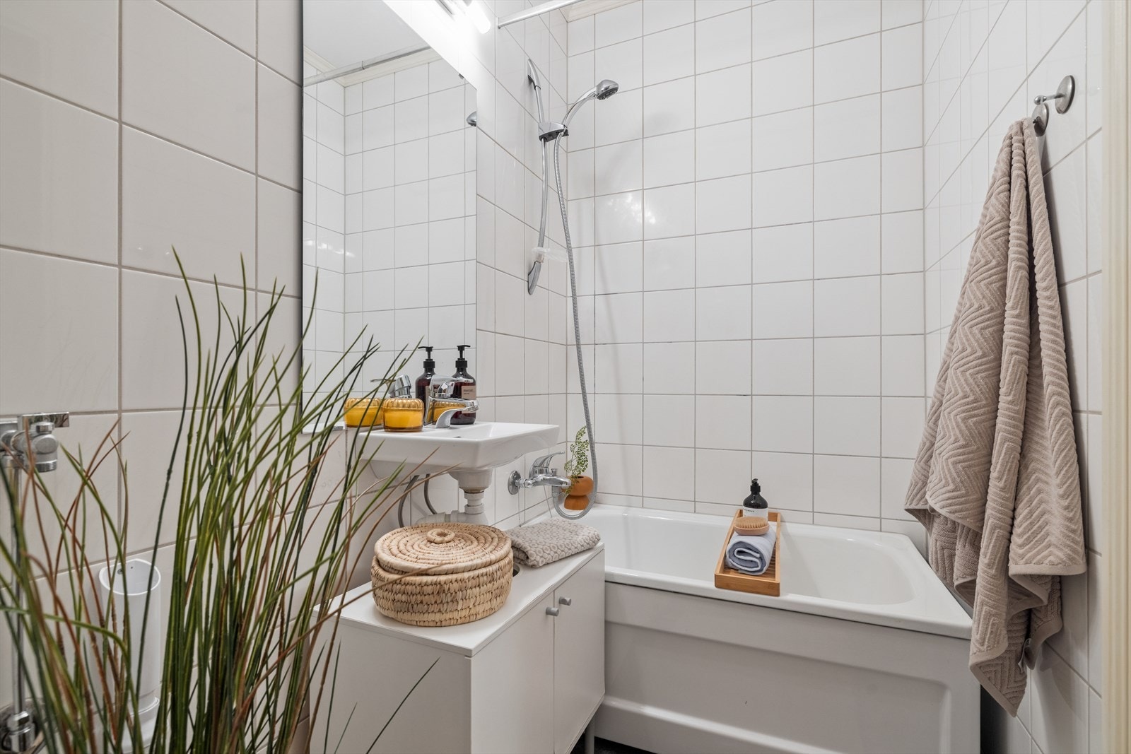 Flislagt bad fra 2010 med badekar, servant med ett greps blandebatteri og vegghengt toalett. Galleribilde