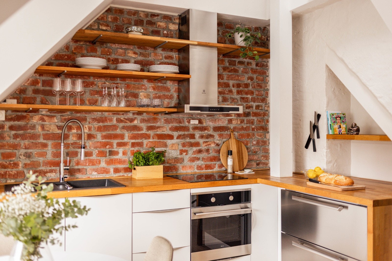 Lyst og pent Kvik-kjøkken fra 2014 med hvite glatte fronter og heltre benkeplate med nedfelt oppvaskkum. Både praktisk og dekorativt med vegghengte hyller med belysning under. Galleribilde