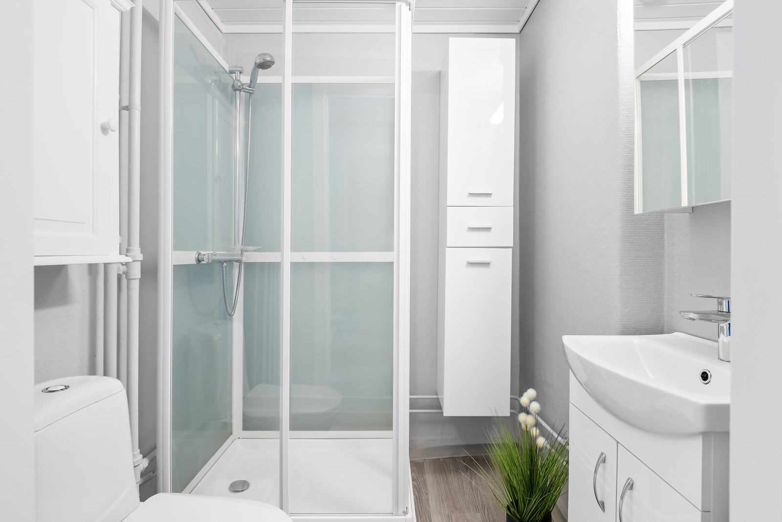 Baderomsgulvet er belagt med klikkvinyl og det er veggflater med malt tapet Galleribilde