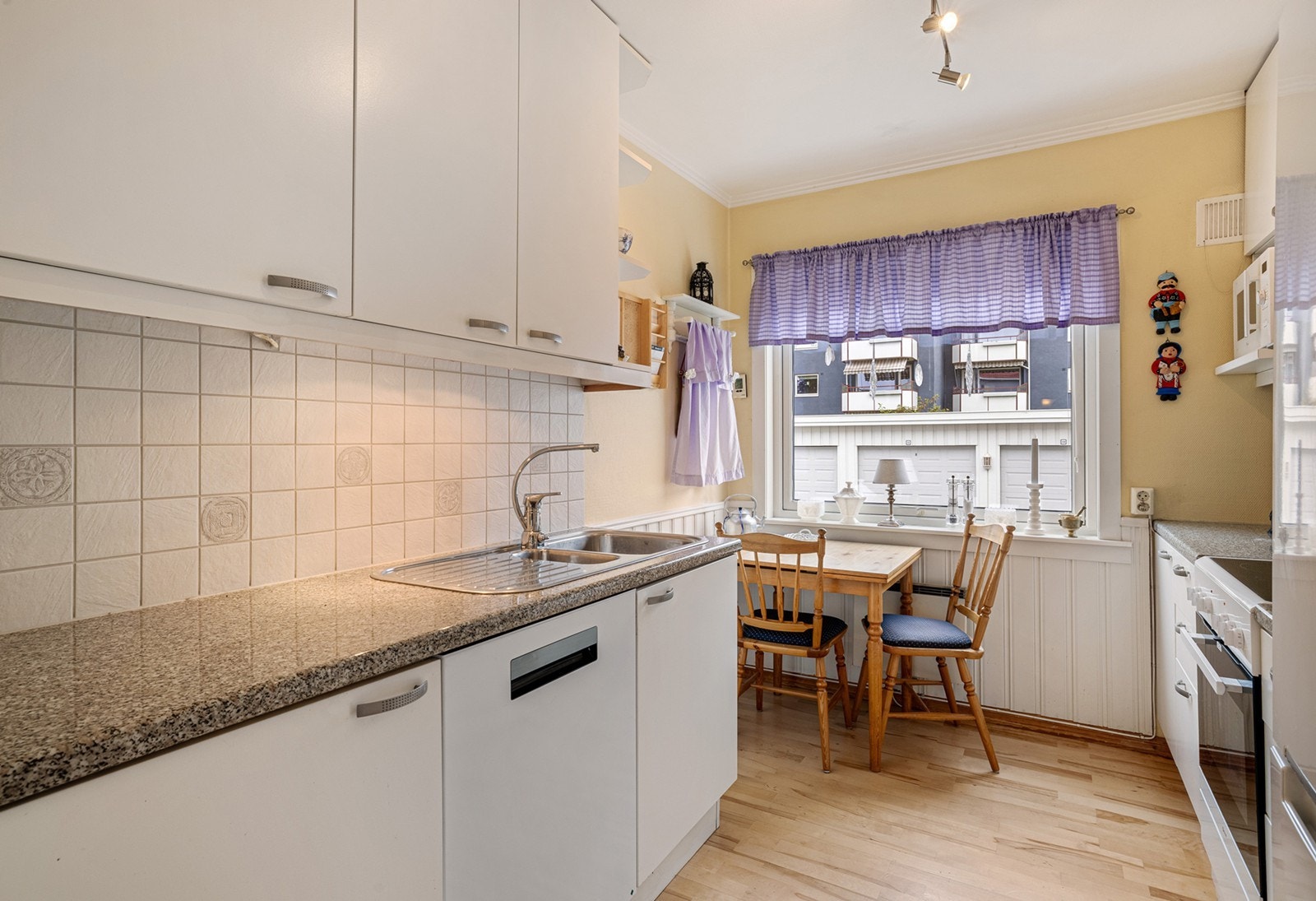 Hvit kjøkkeninnredning med glatte fronter og med laminert benkeplate med nedfelt oppvaskkum med 1-greps blandebatteri. Galleribilde