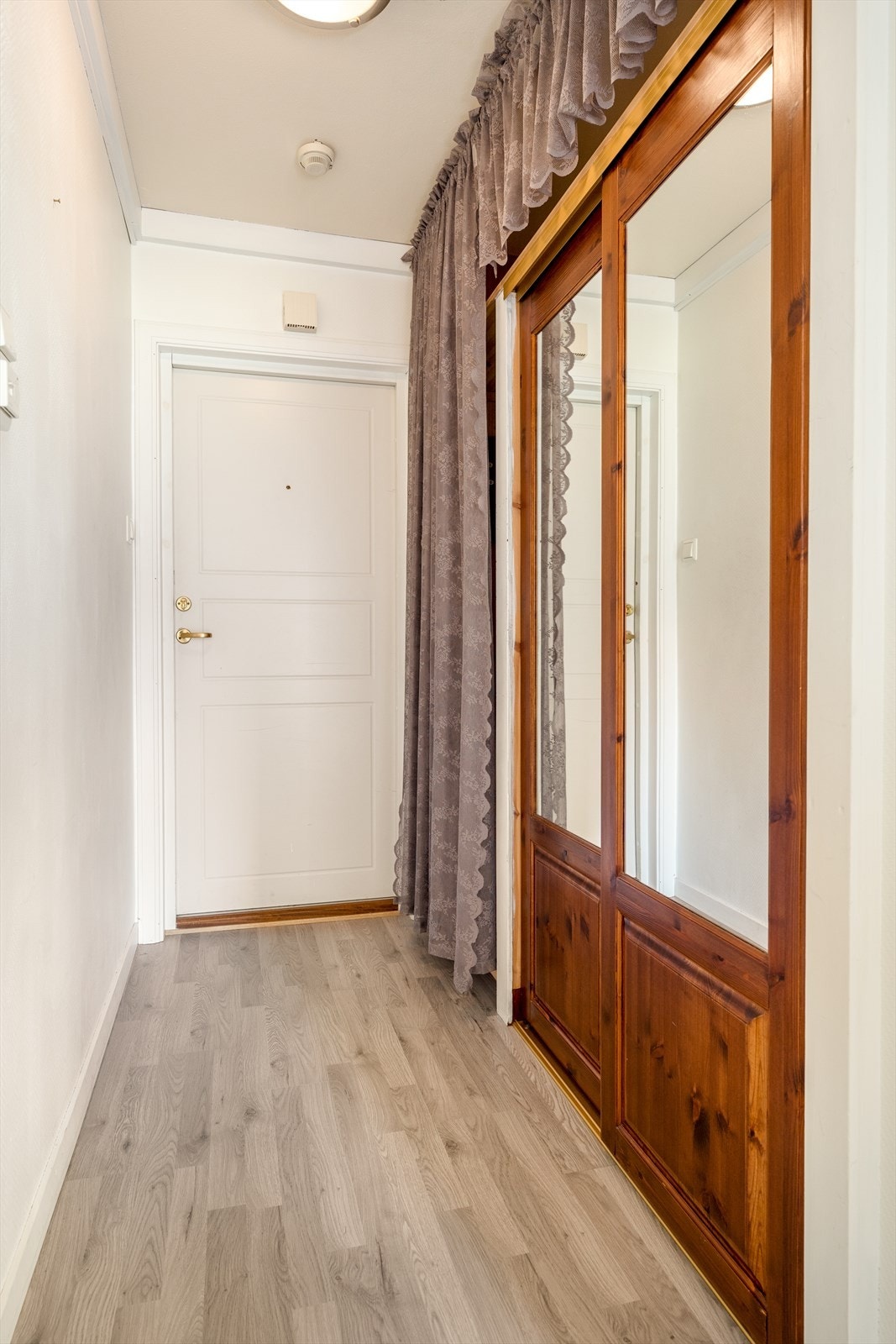 Velkommen inn! Entré med garderobeløsning som har plass til sko og yttertøy. Her er det er laminat på gulv, malt tapet og malt tak. Galleribilde