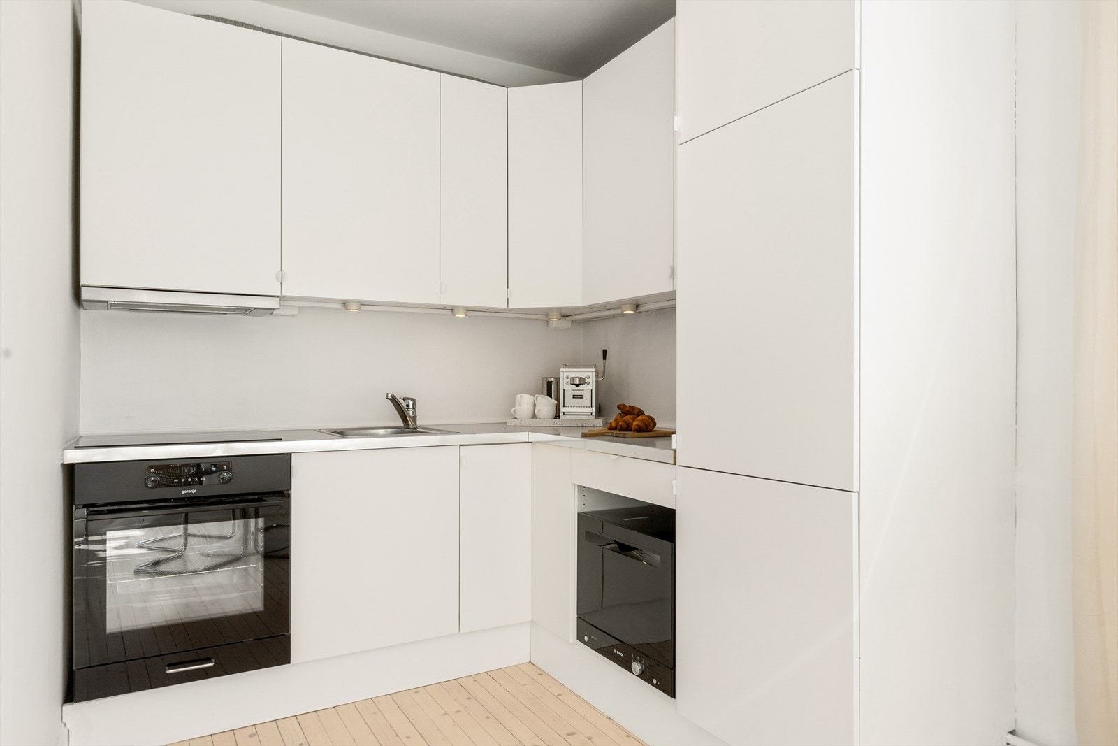 En stilren kjøkkeninnredning med integrerte hvitevarer og med mye skapplass. Galleribilde