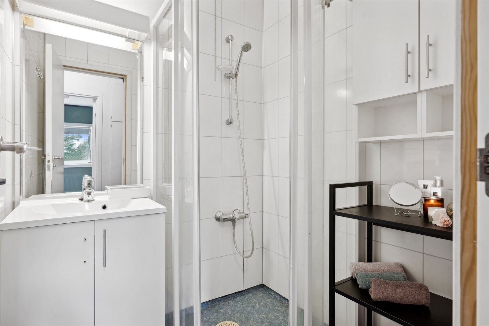 Badet har innredning med servant i seksjon, speil med lys og dusjnisje med skyvedører. Galleribilde