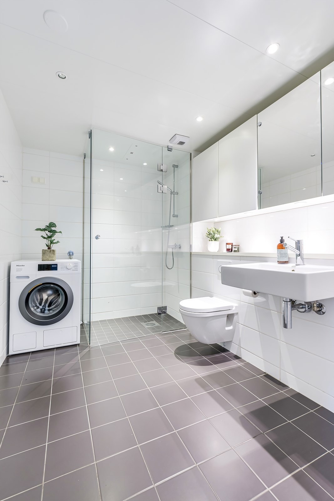 Innredningen består av servant, speilskap, vegghengt skap, vegghent toalett og dusjhjørne med glassdører Galleribilde