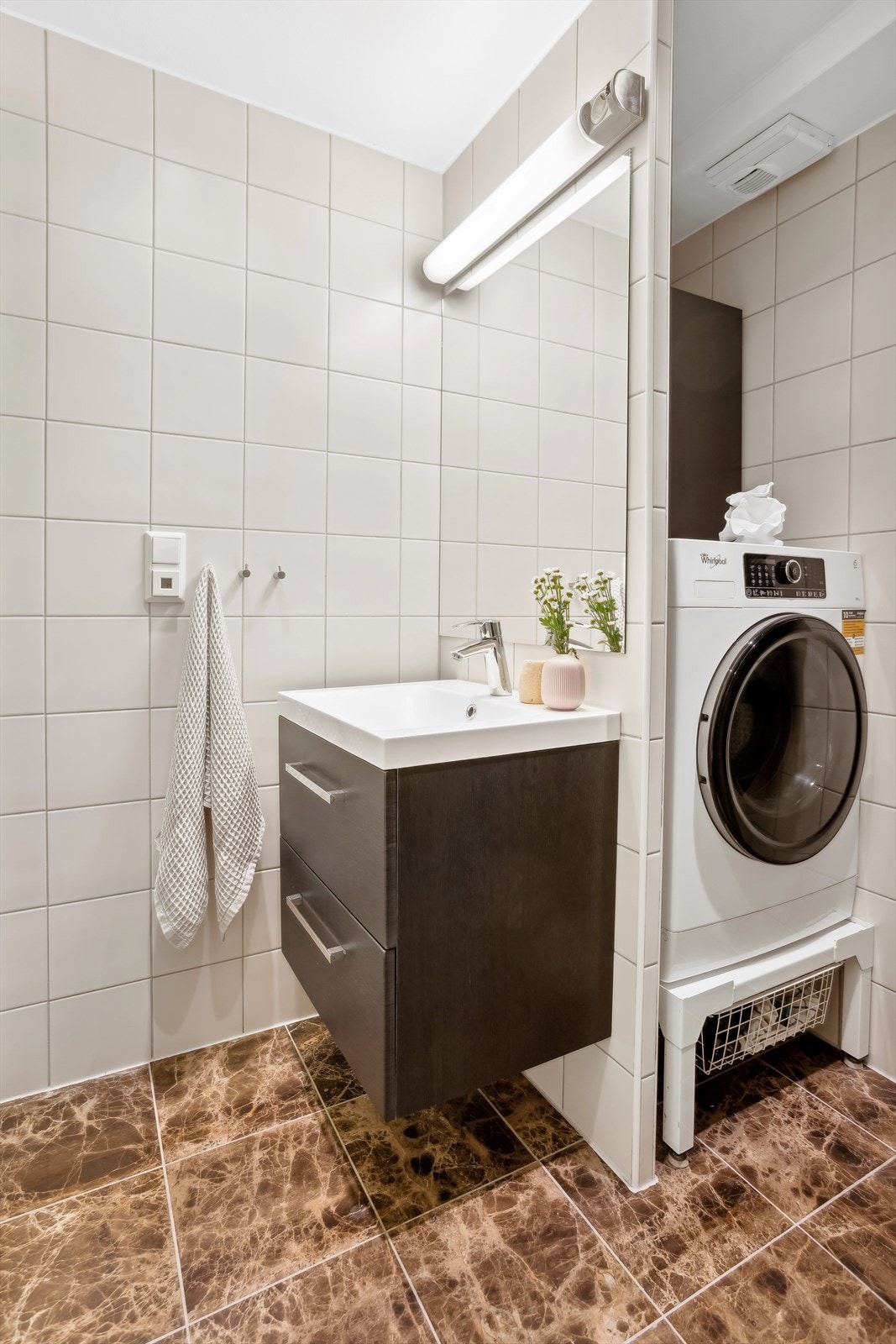 Badet har varmekabler i det stilige gulvet og en smart løsning for oppbevaring av vaskemaskin Galleribilde