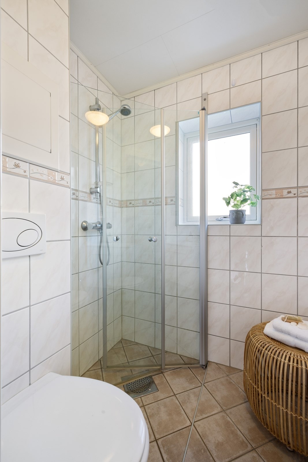 Rommet har innfellbare dusjdører i glass, vegghengt toalett, speilskap og servantinnredning Galleribilde