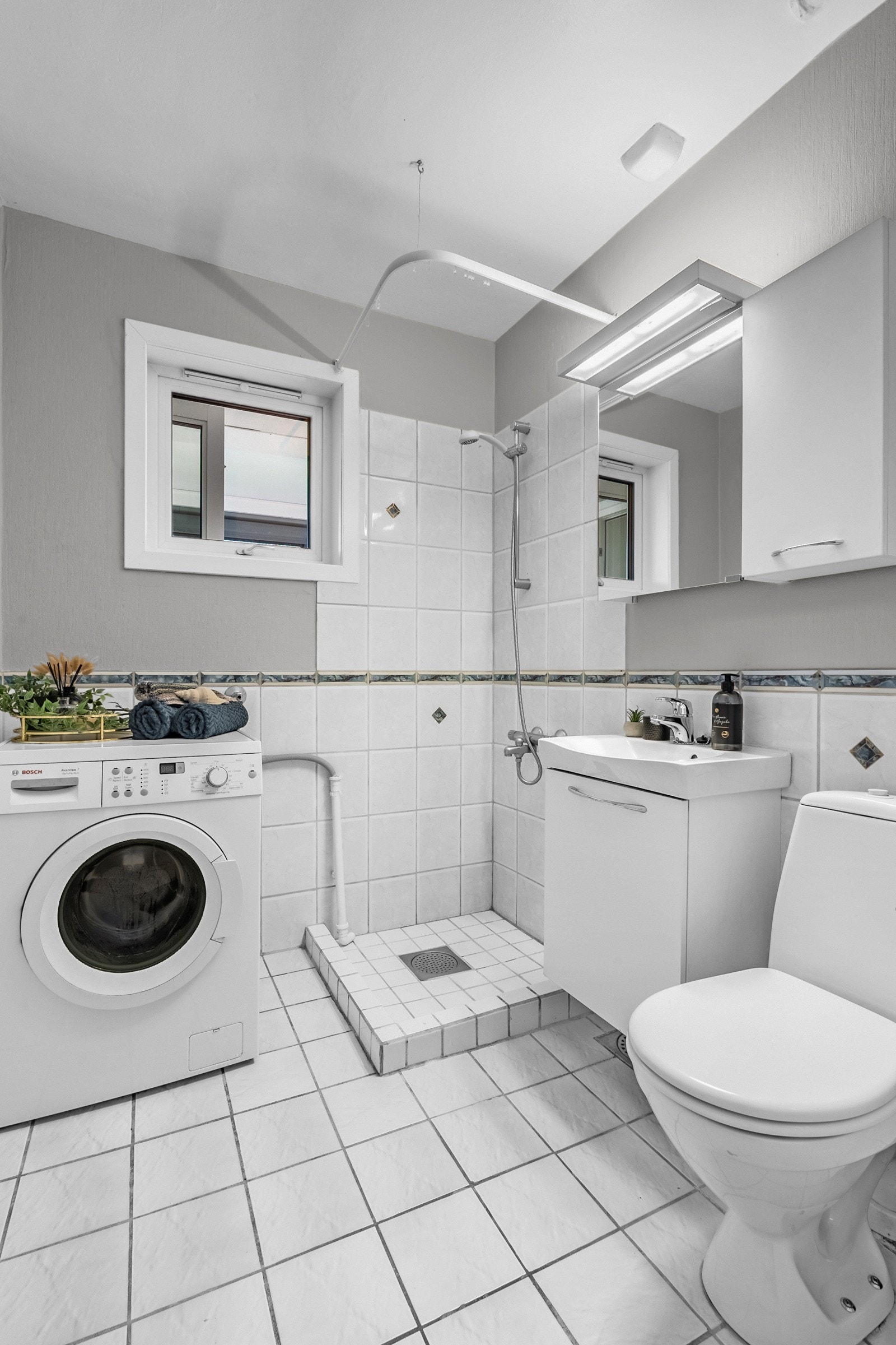 Badet har fliser på gulv med gulvvarme, samt veggfliser til brystningshøyde og et flislagt dusjhjørne Galleribilde