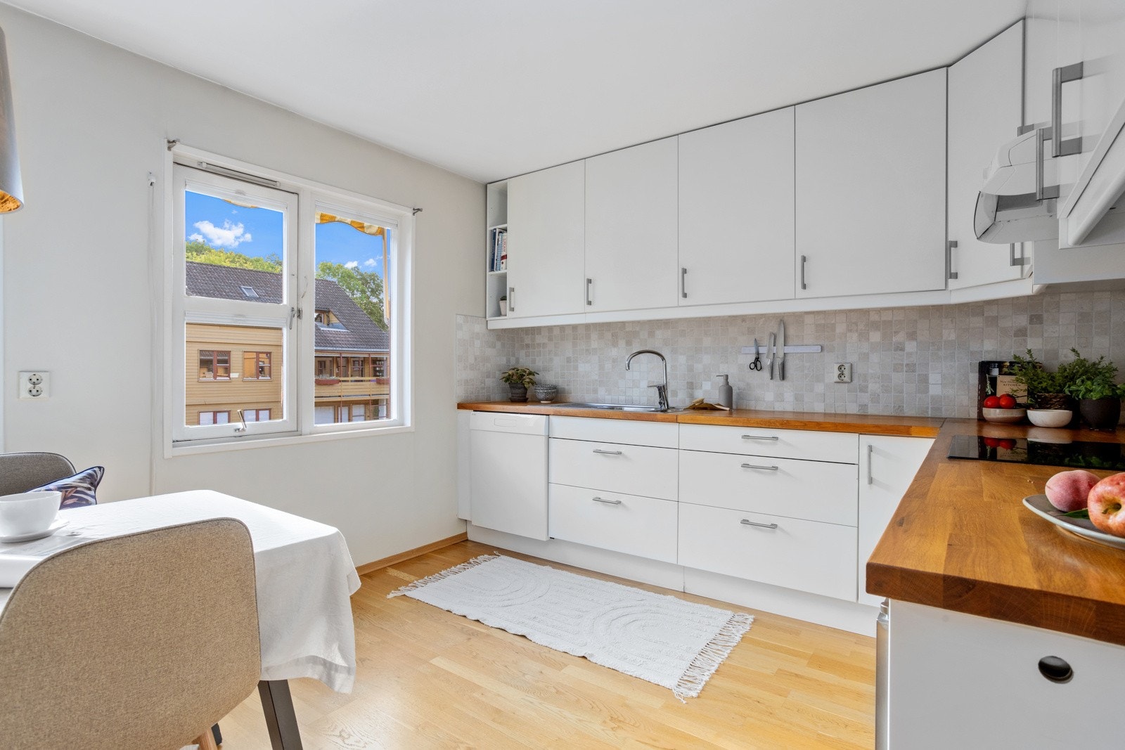 Kjøkken med hvit glatt kjøkkeninnredning med heltre benkeplater. Galleribilde