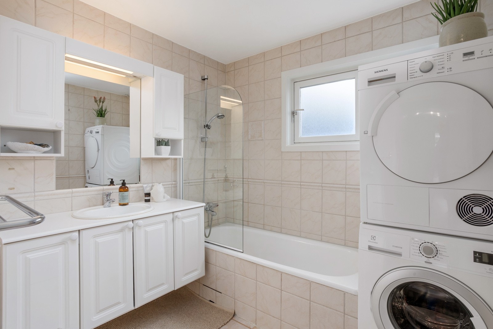 Flislagt bad med badekar og opplegg for vaskemaskin. Galleribilde