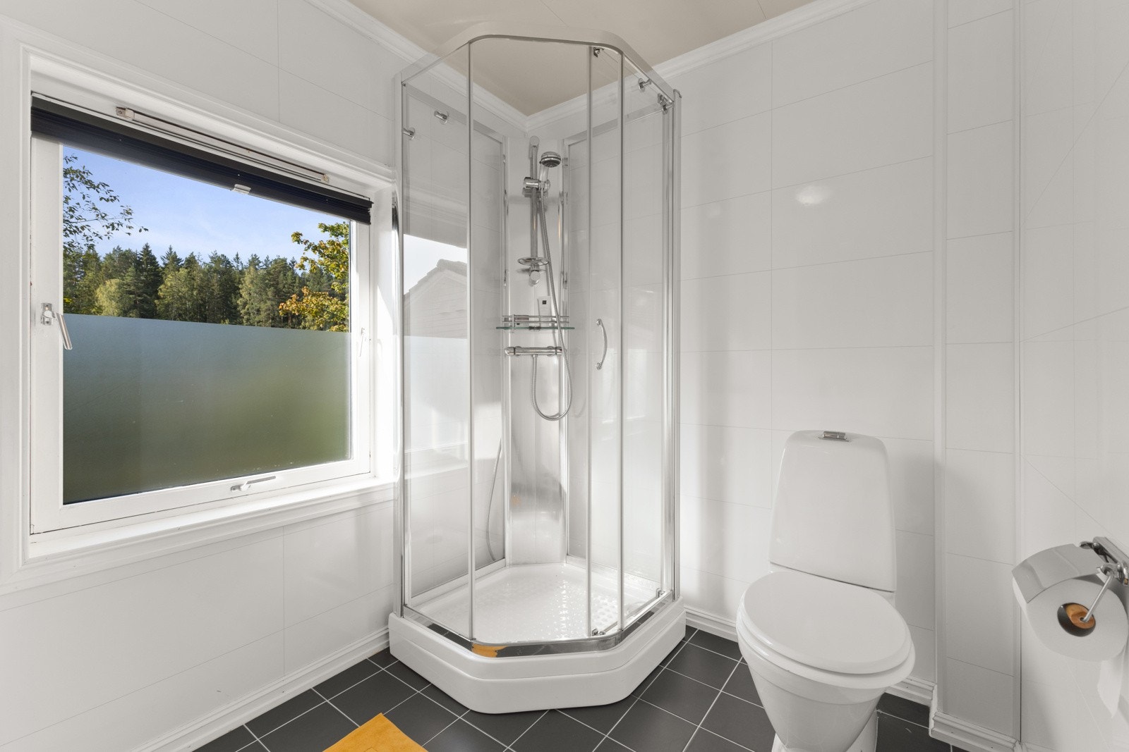 Badet har også dusjkabinett med delvegger og skyvedør av glass. Det er gulvstående toalett og opplegg for vaskemaskin. Galleribilde