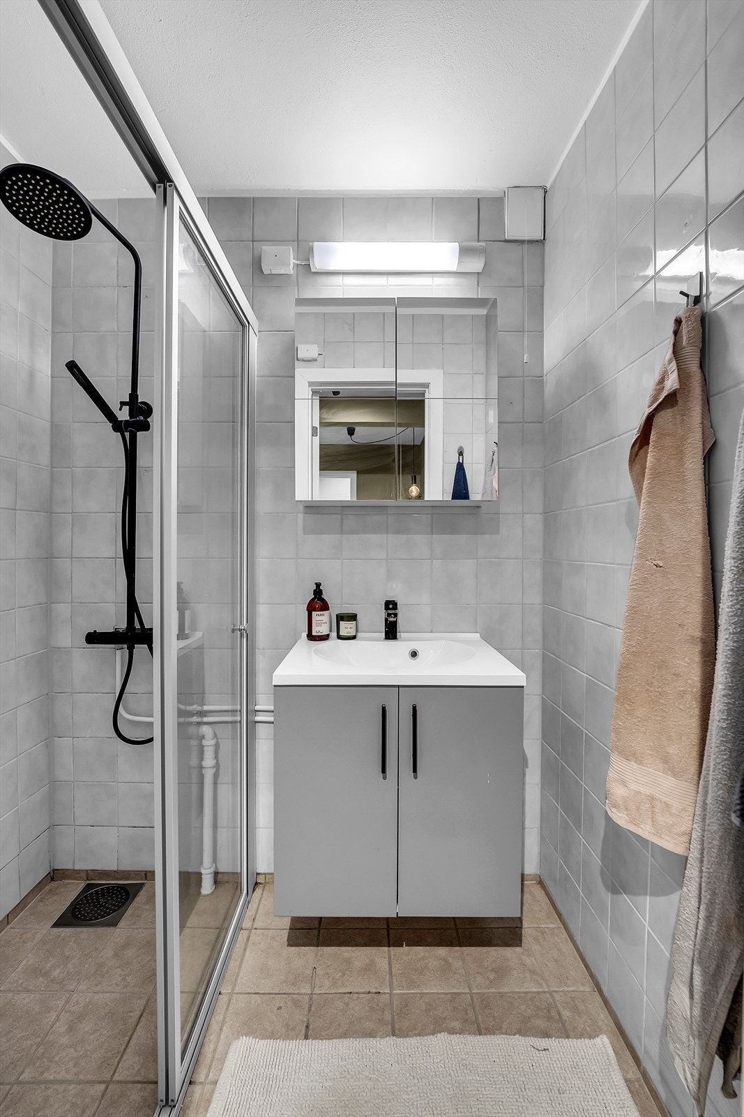 Bad med flislagte vegger og gulv med gulvvarme. Her er det servantinnredning og dusj med skyvedører. Galleribilde