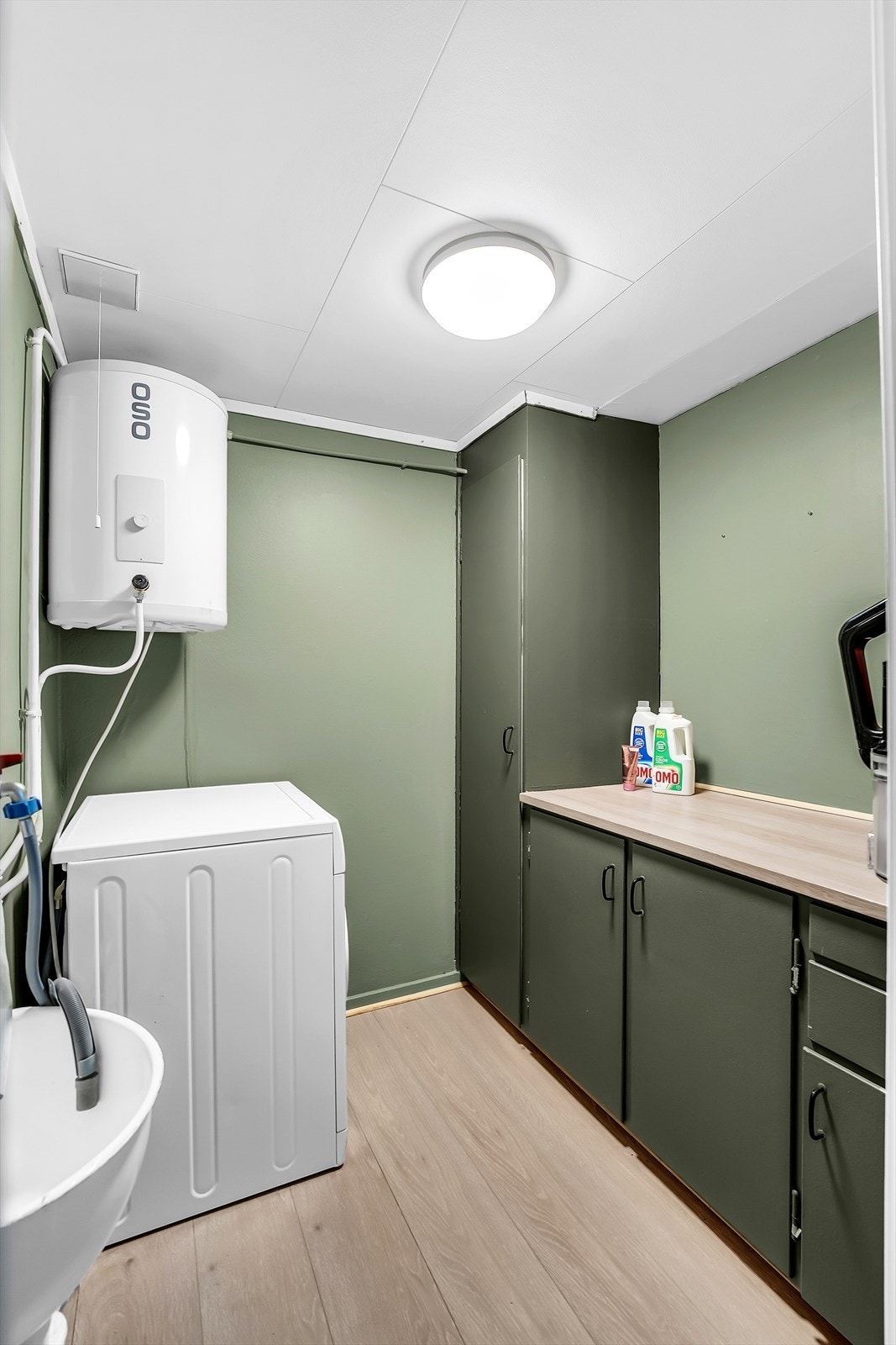 Teknisk rom med opplegg for vaskemaskin og oppbevaring. Galleribilde