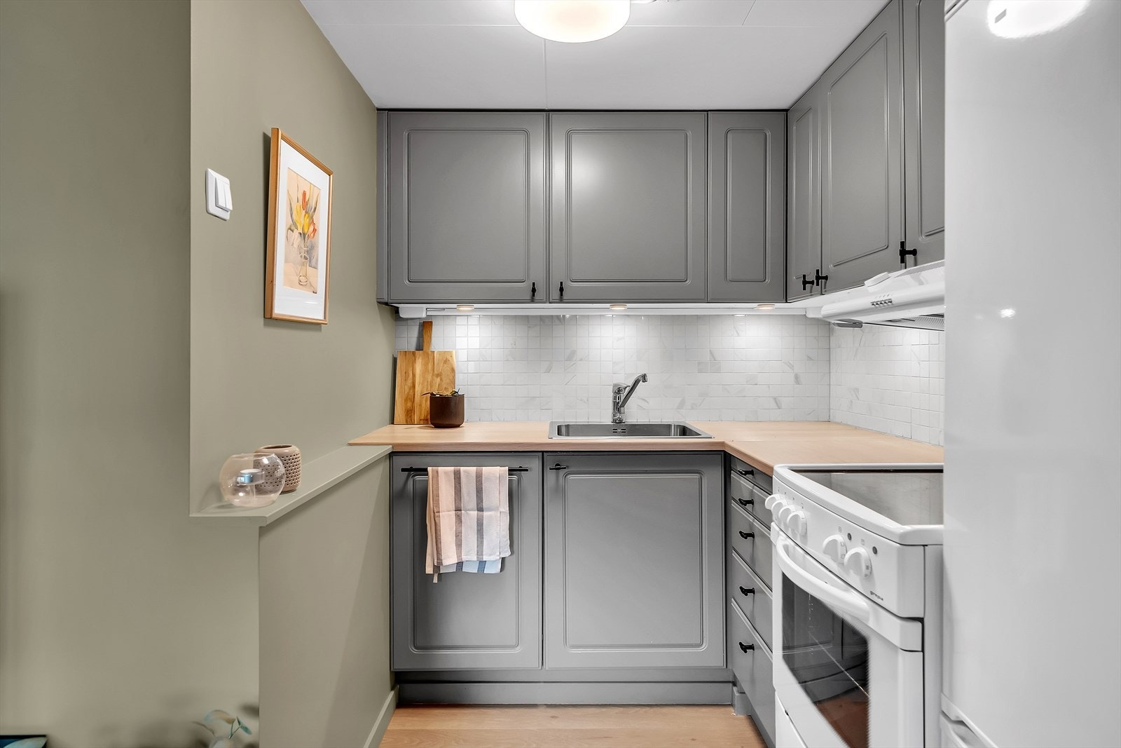 Kjøkkeninnredning med grå, profilerte fronter og benkeplate av laminat. Galleribilde