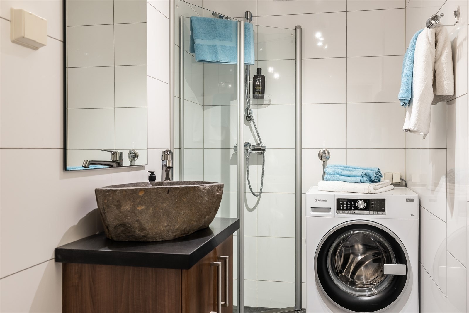 Badet er utstyrt med mekanisk avtrekk, innfellbare dusjdører, veggmontert wc og servantskap med ettgreps blandebatteri fra IKEA Galleribilde