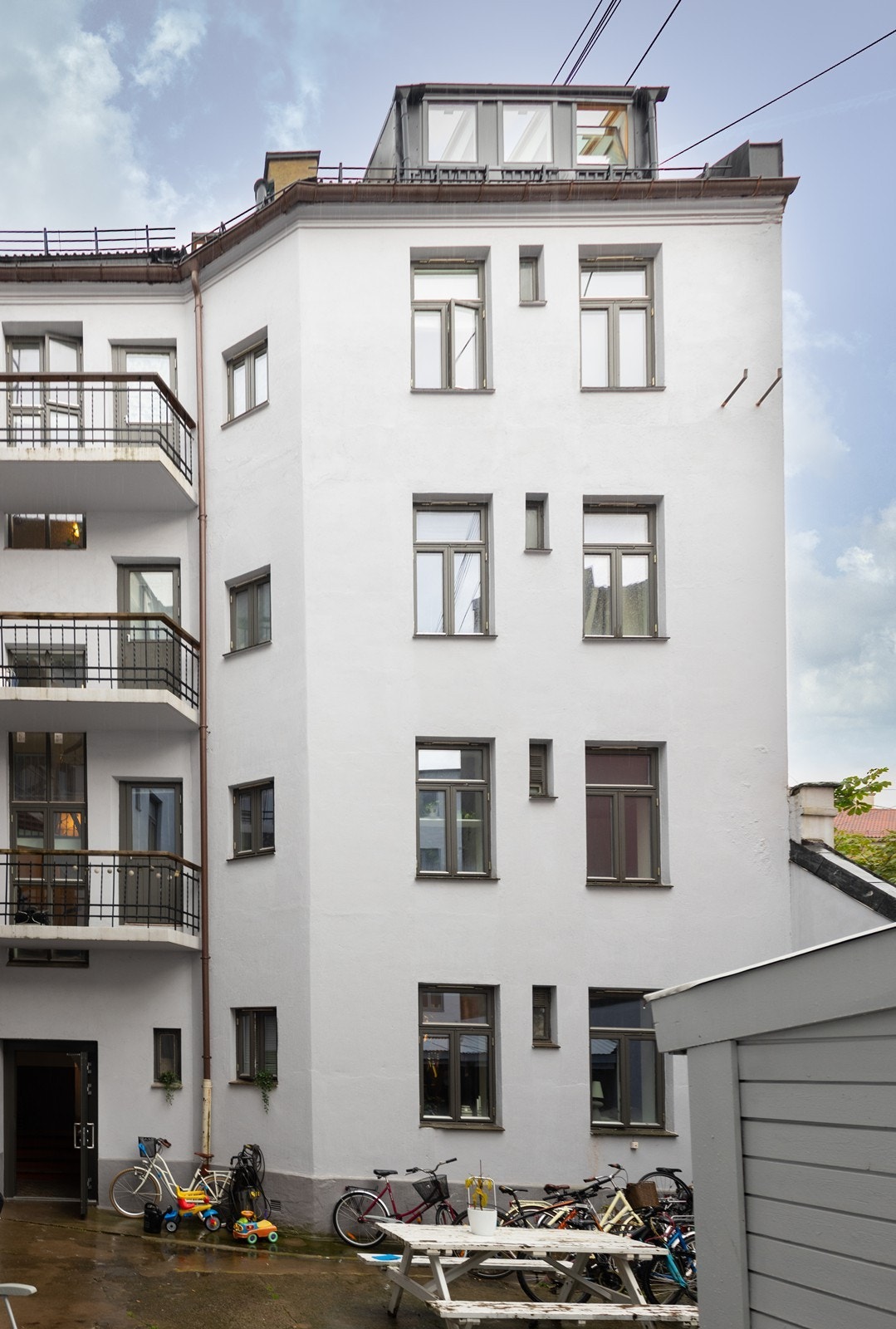 Pen fasade, her sett fra bakgården. Båkgård med sittegruppe og sykkelparkering. Galleribilde