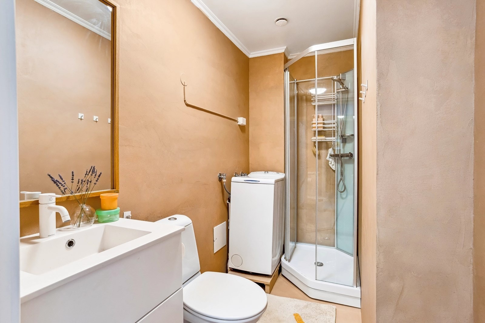 Badet består av frittstående wc, speil, dusjkabinett og opplegg for vaskemaskin Galleribilde