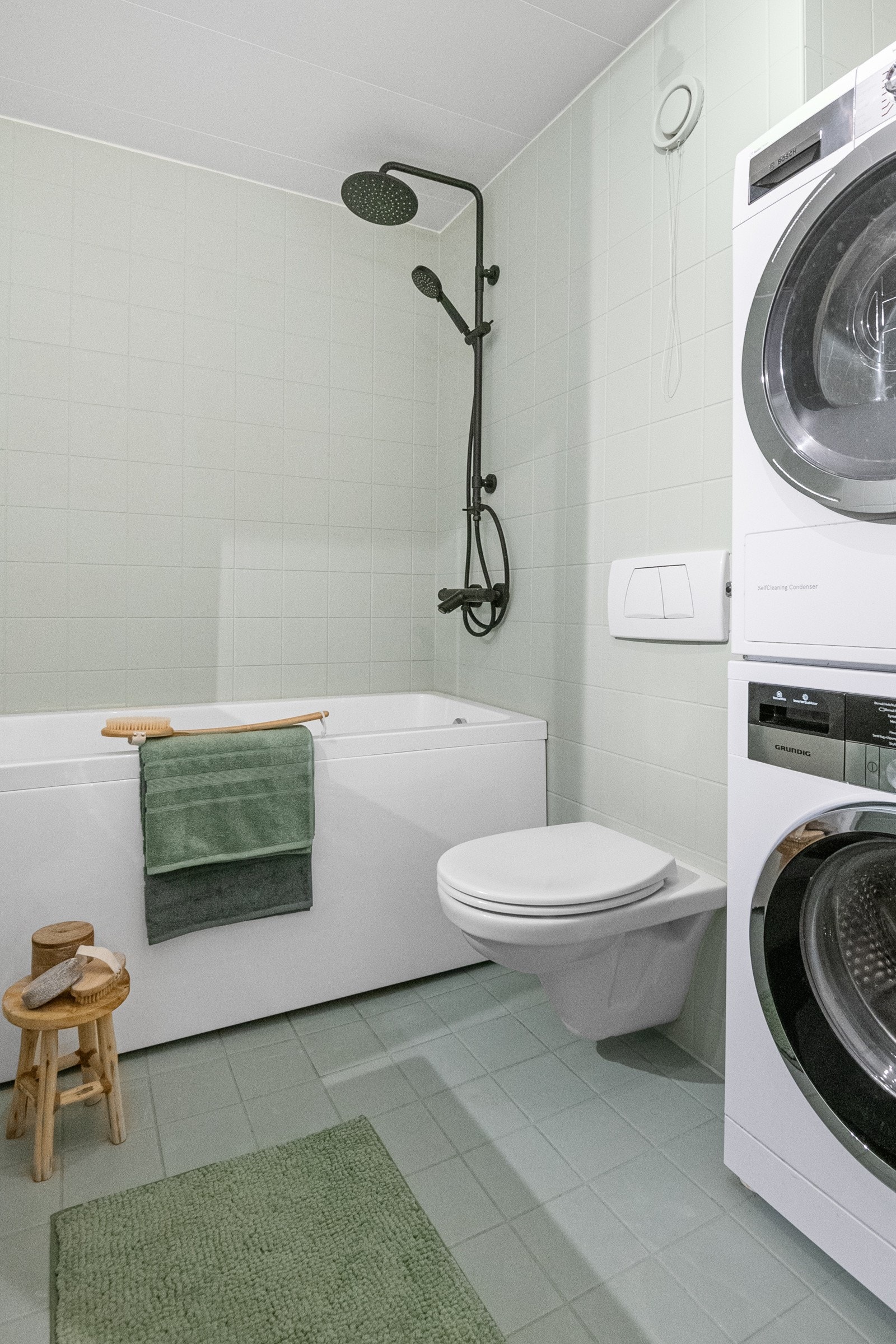 Badet er flislagt med varmekabler i gulv og veggmontert toalett. En praktisk baderomsinnredning sørger for mye oppbevaringsplass. Opplegg til vaskemaskin og plass for tørketrommel i en egen nisje som gir maksimalt utbytte av plassen. Galleribilde