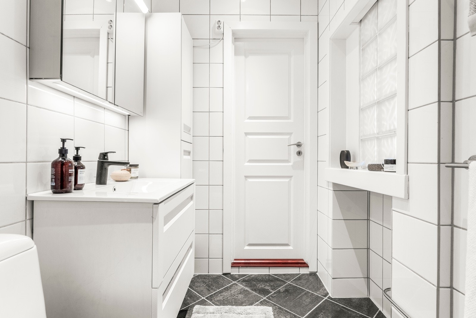 På badet finner du toalett, servantskap, overskap med speilfronter, høyskap og dusjhjørne, samt opplegg til vaskemaskin Galleribilde