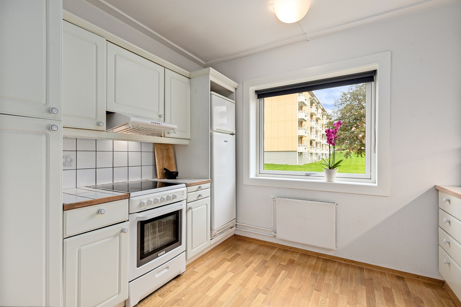 Kjøkkenet består av vitrineskap med glassfronter og flislagt kjøkkenbenk. Kjøkkenet har skyllekum i rustfrittstål, belysninger under overskap, opplegg for oppvaskmaskin og frittstående hvitevarer. Galleribilde