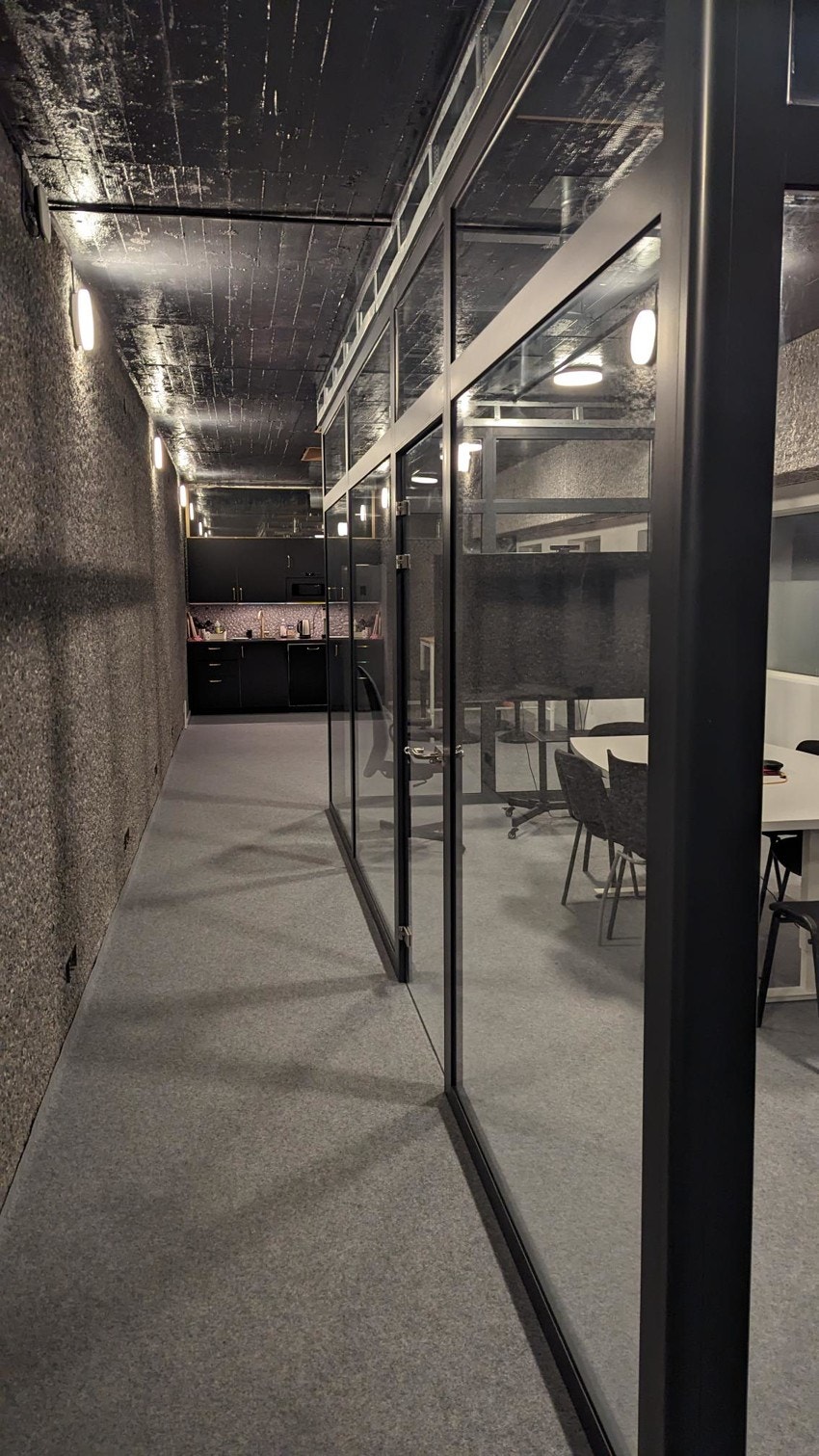 Kontorceller og møterom avdelt med glassvegger og dører innrammet med svarte karmer Galleribilde