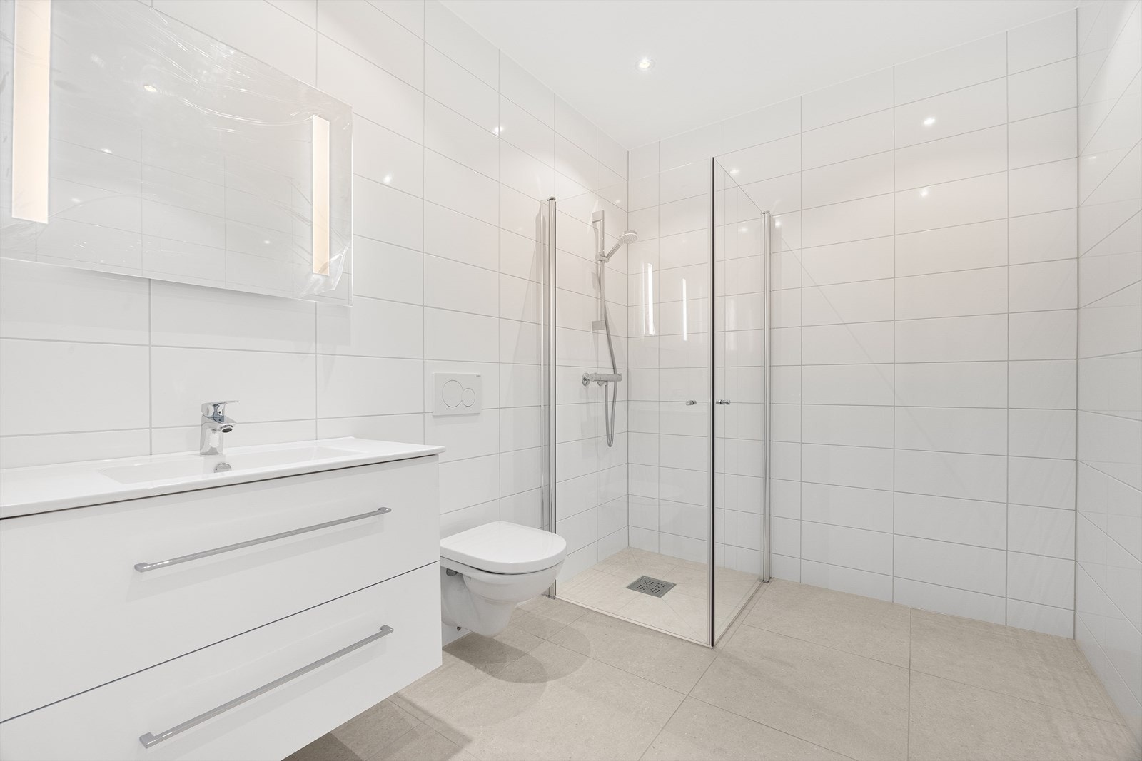 Lekkert helfliset baderom med servant, møblement, speil, belysning og dusjhjørne. Galleribilde