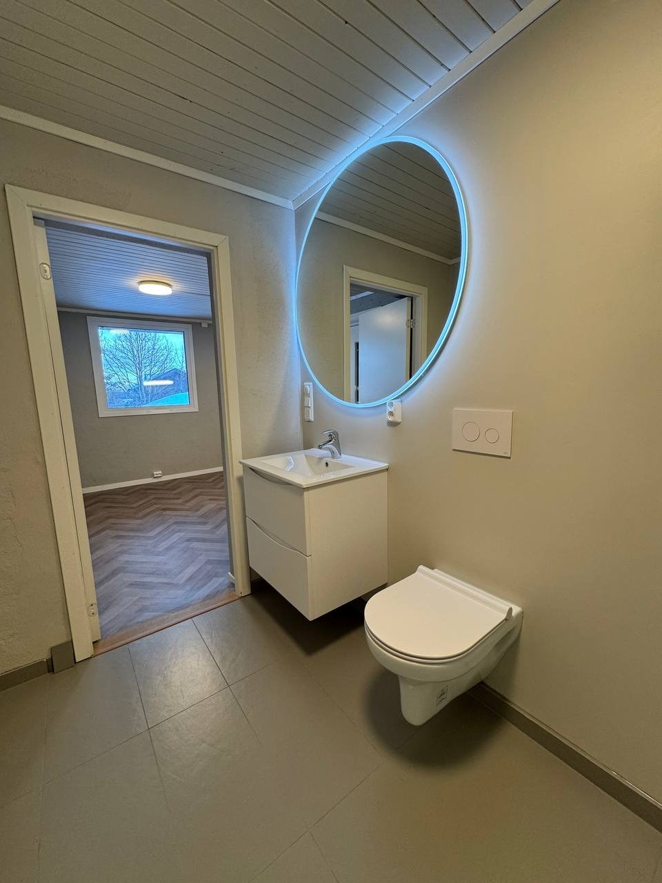 Pent Vikingbad-møbel og speil. Vegghengt toalett. Fliser på gulv. Galleribilde