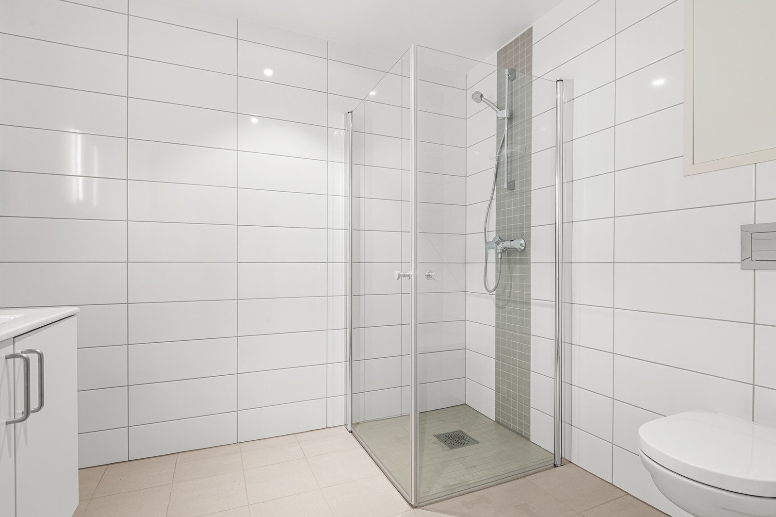 Badet er utstyrt med gulvvarme, dusjhjørne, vegghengt toalett og servant m/lagring Galleribilde