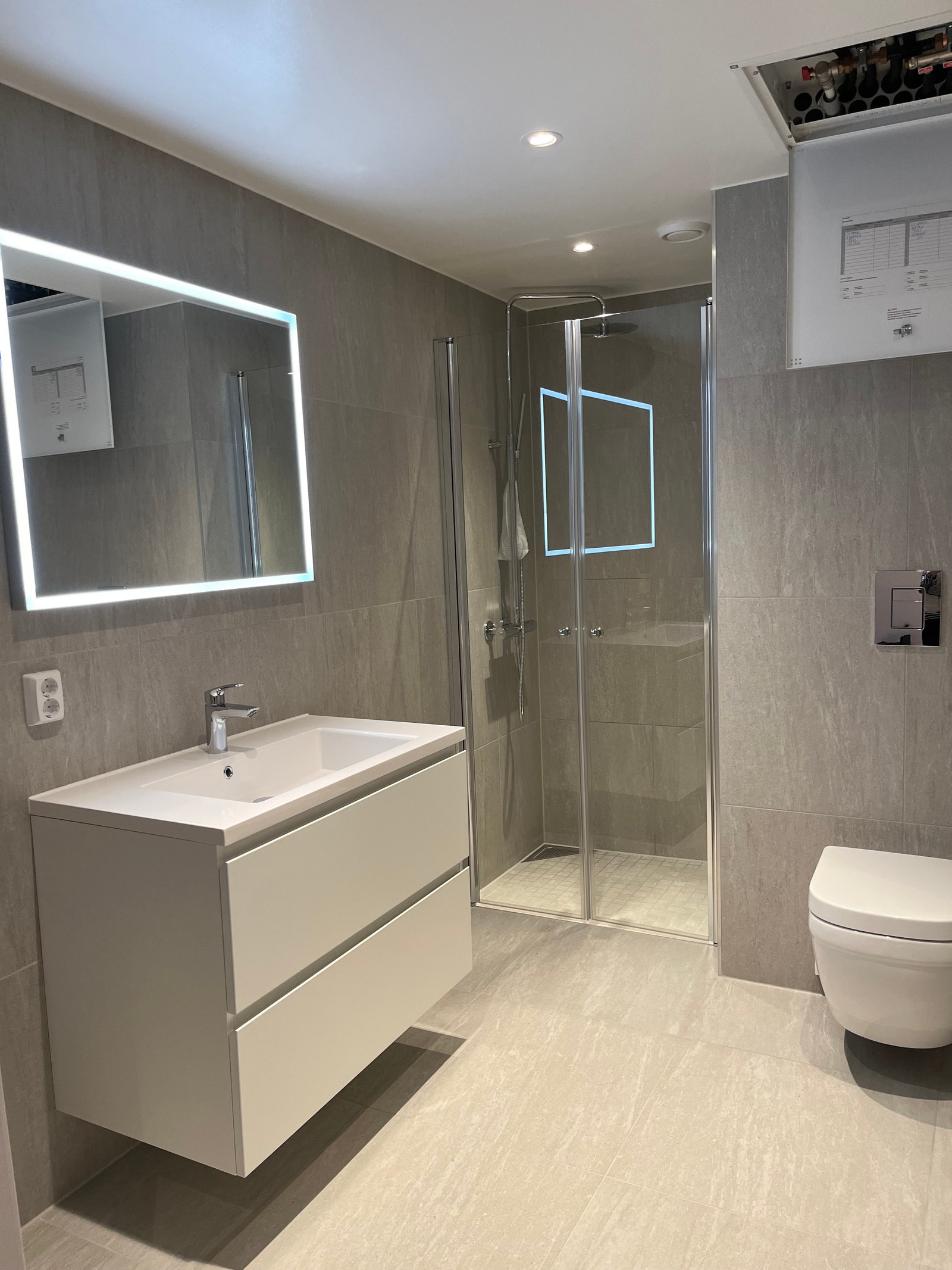 Bad med vask/tørk til venstre for vask. Flisebelagt gulv og vegger. Galleribilde